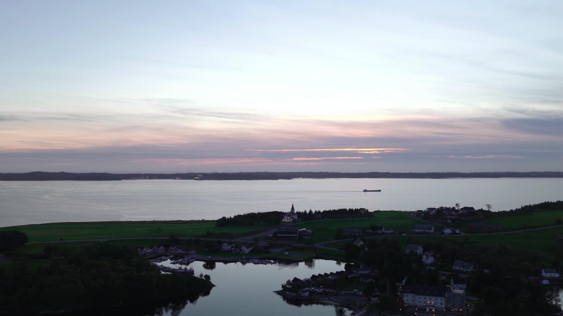 Coastal village at sunrise with church and bay, Herdla