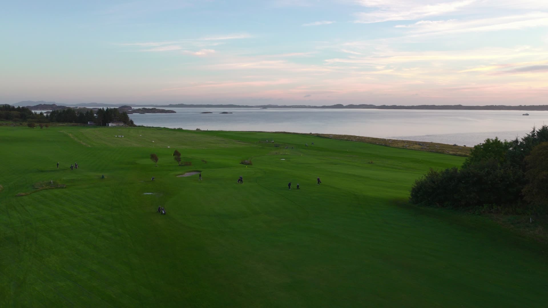 Green field with scattered visitors at waterfront, Herdla