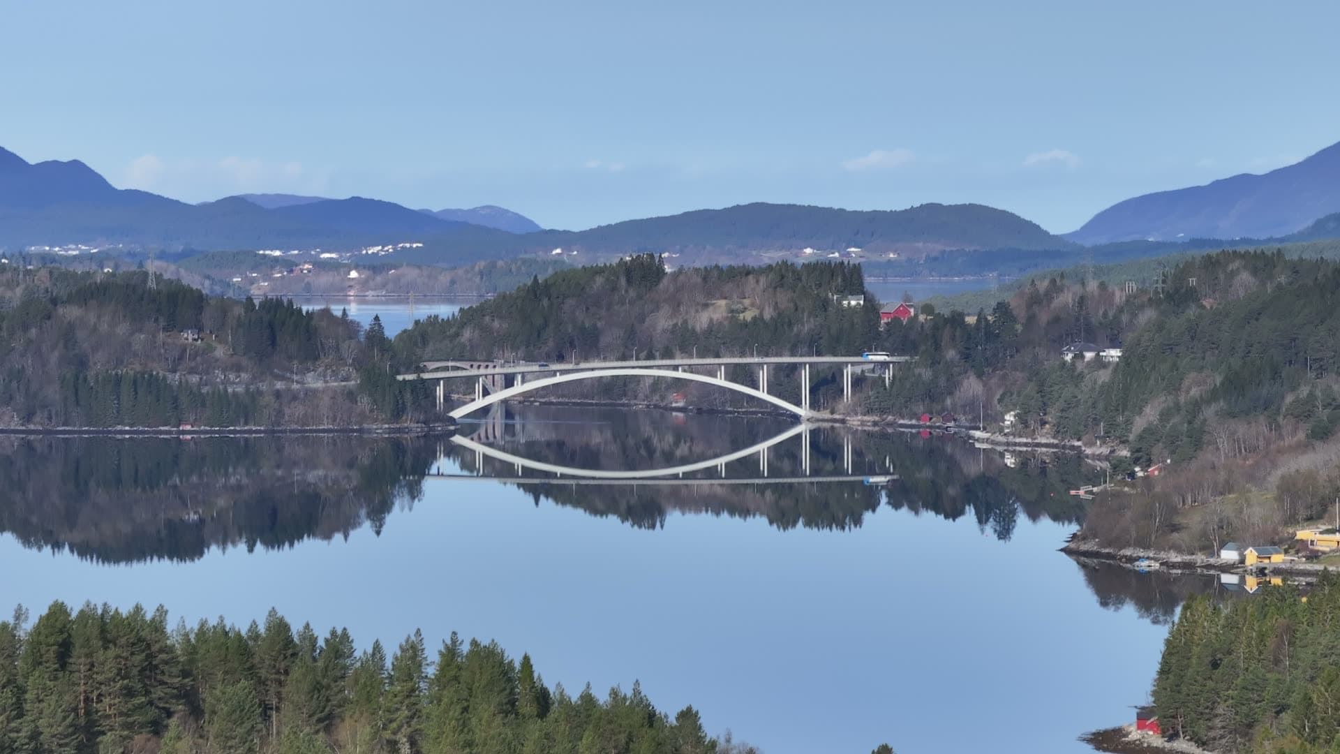 Skodjebrua arch bridge reflected in calm water, Norway