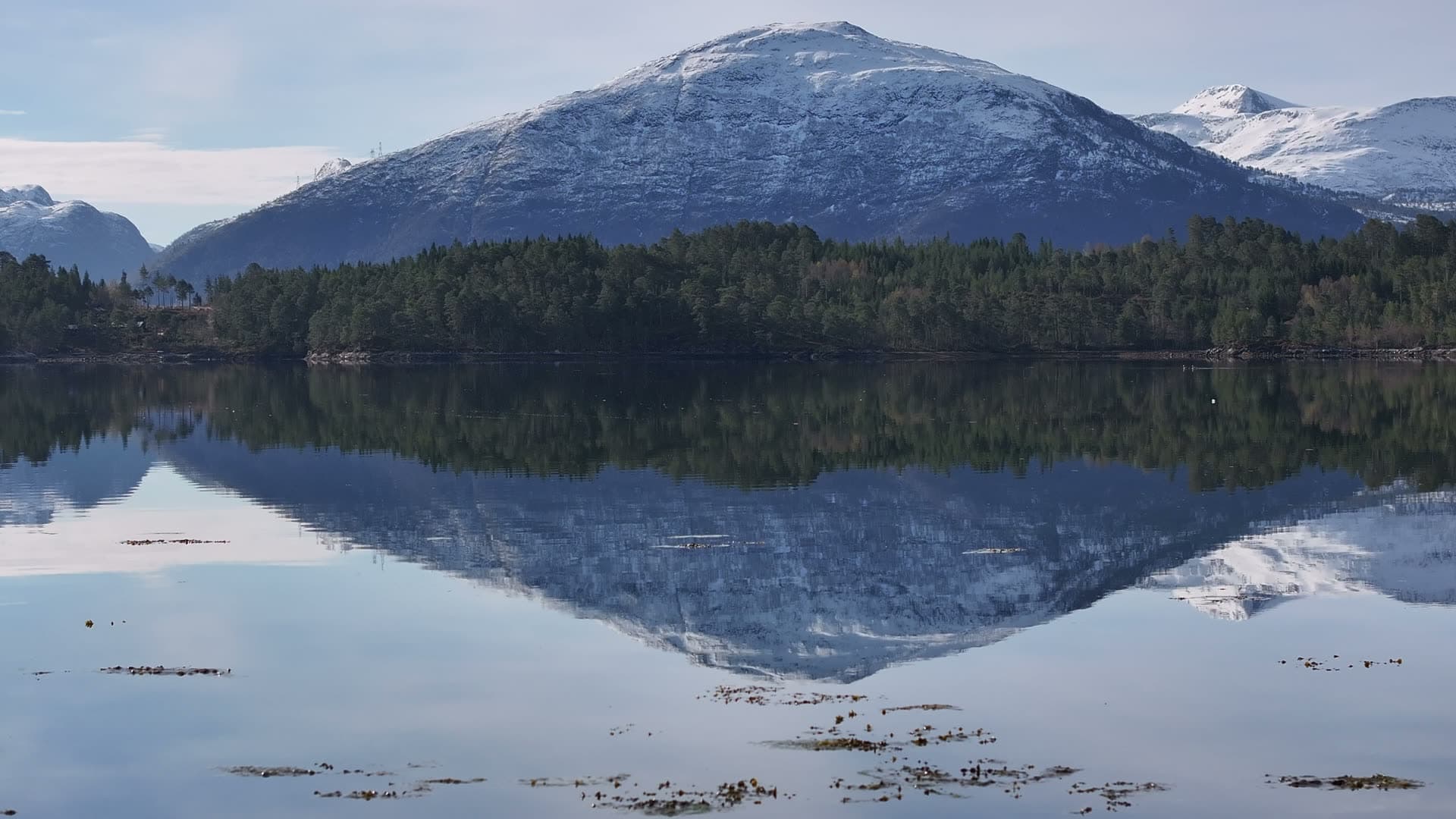 Snow covered mountain mirrored in still water near Skodje, Norway