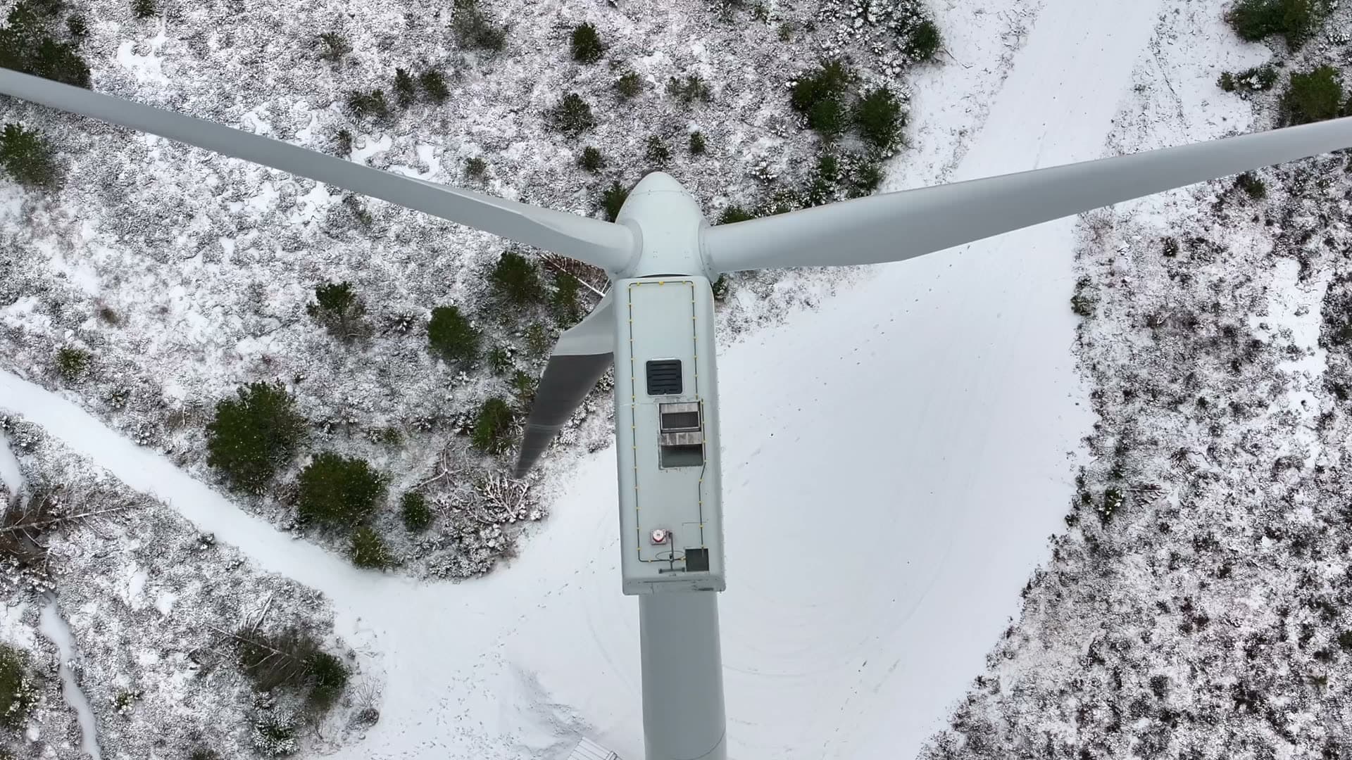 Top down view of wind turbine blades above snowy woodland, Harøy