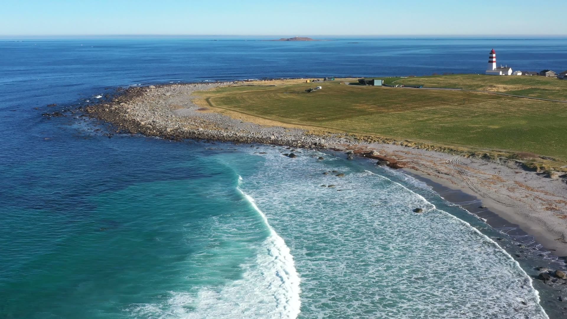 Ocean waves along Alnes beach beneath the lighthouse