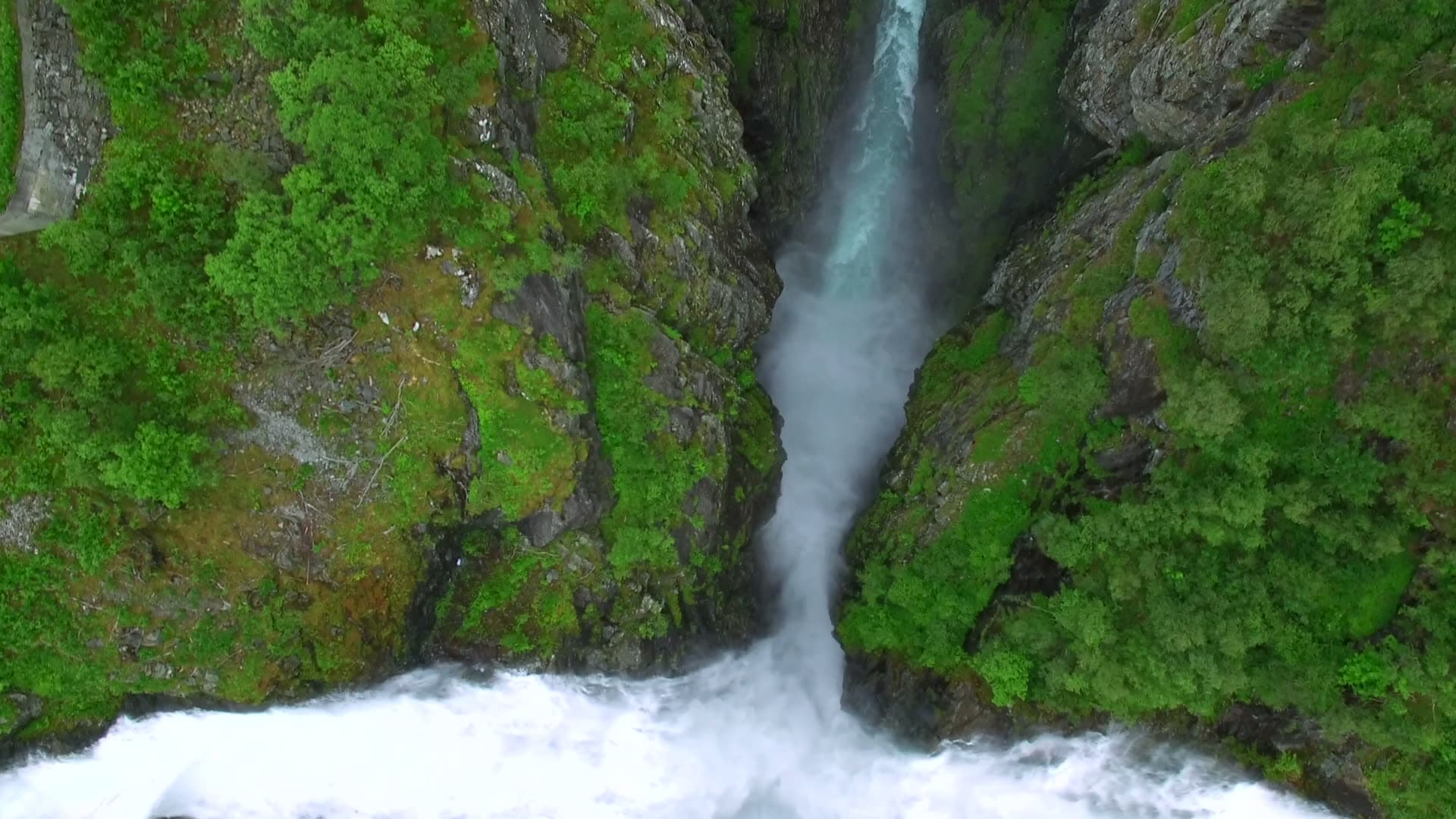Overhead aerial descent from Zakariasdammen spillway into a deep gorge