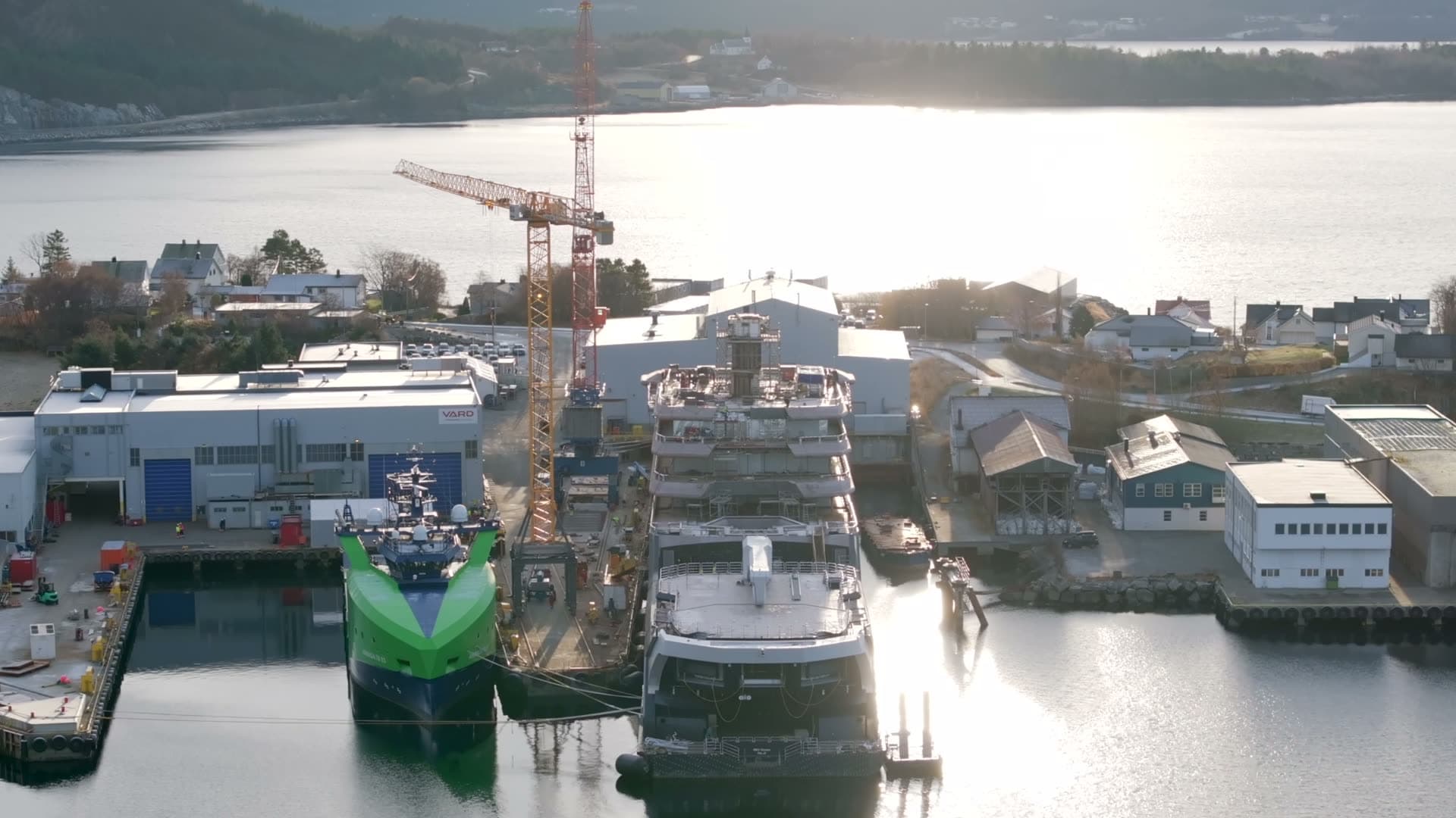 Rear view of REV Ocean and shipyard cranes above reflective water