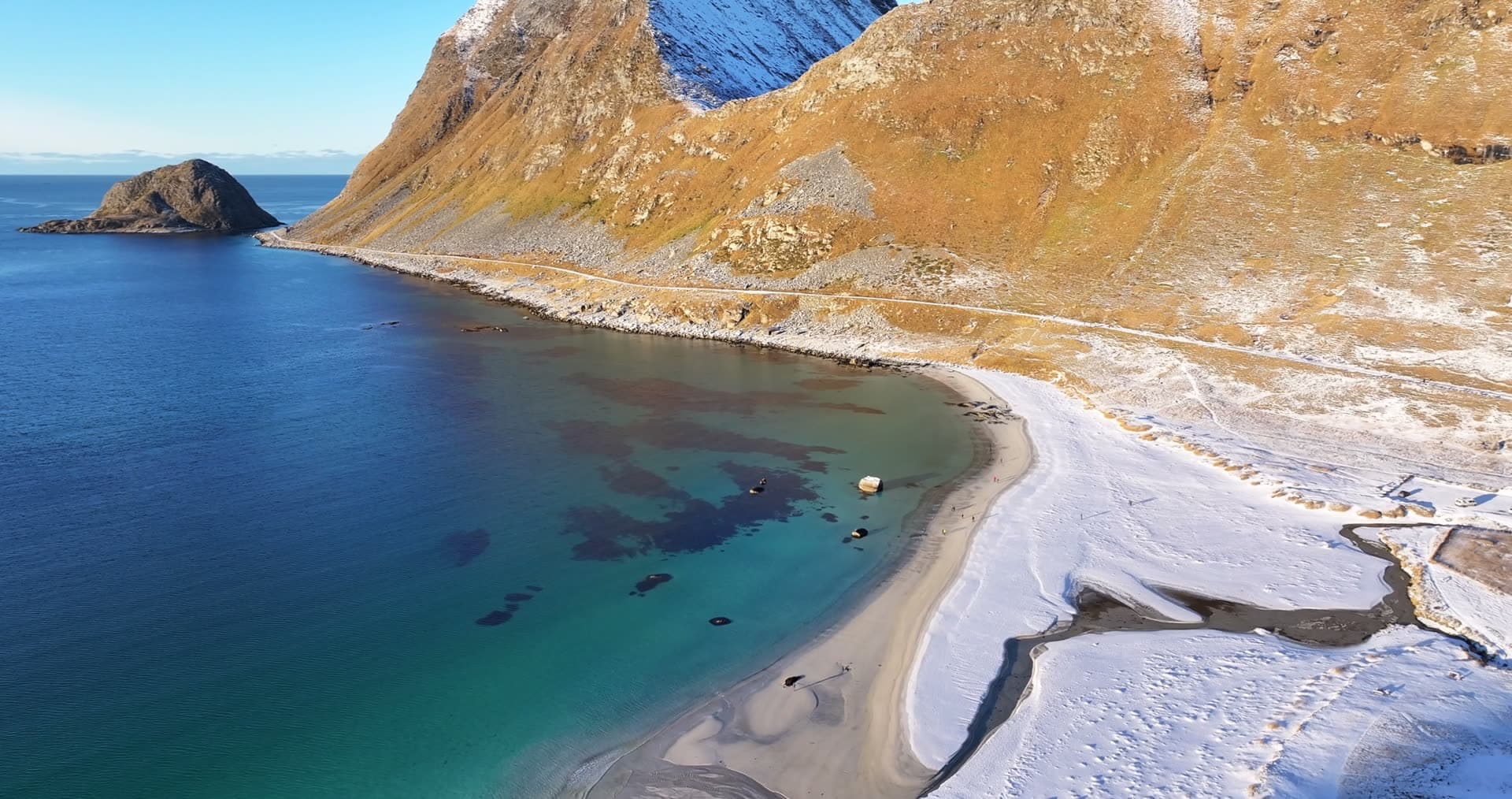 Snow covered beach and turquoise coastal water at Vik in Lofoten