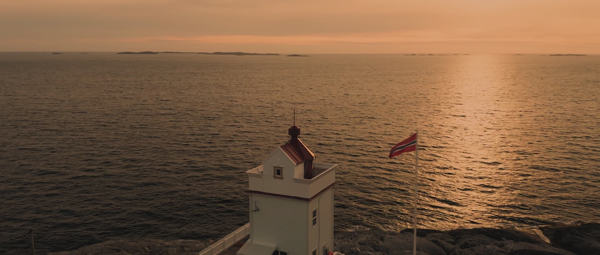 Lighthouse at sunset over calm ocean, Sveio
