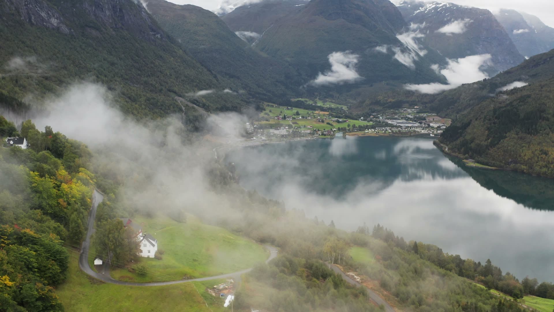 Alpine lake with mountain mist and valley village, Innvikfjorden