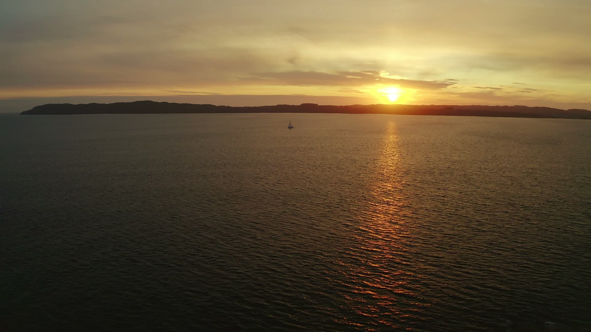 Sailboat at sunset over island and calm sea, Sveio