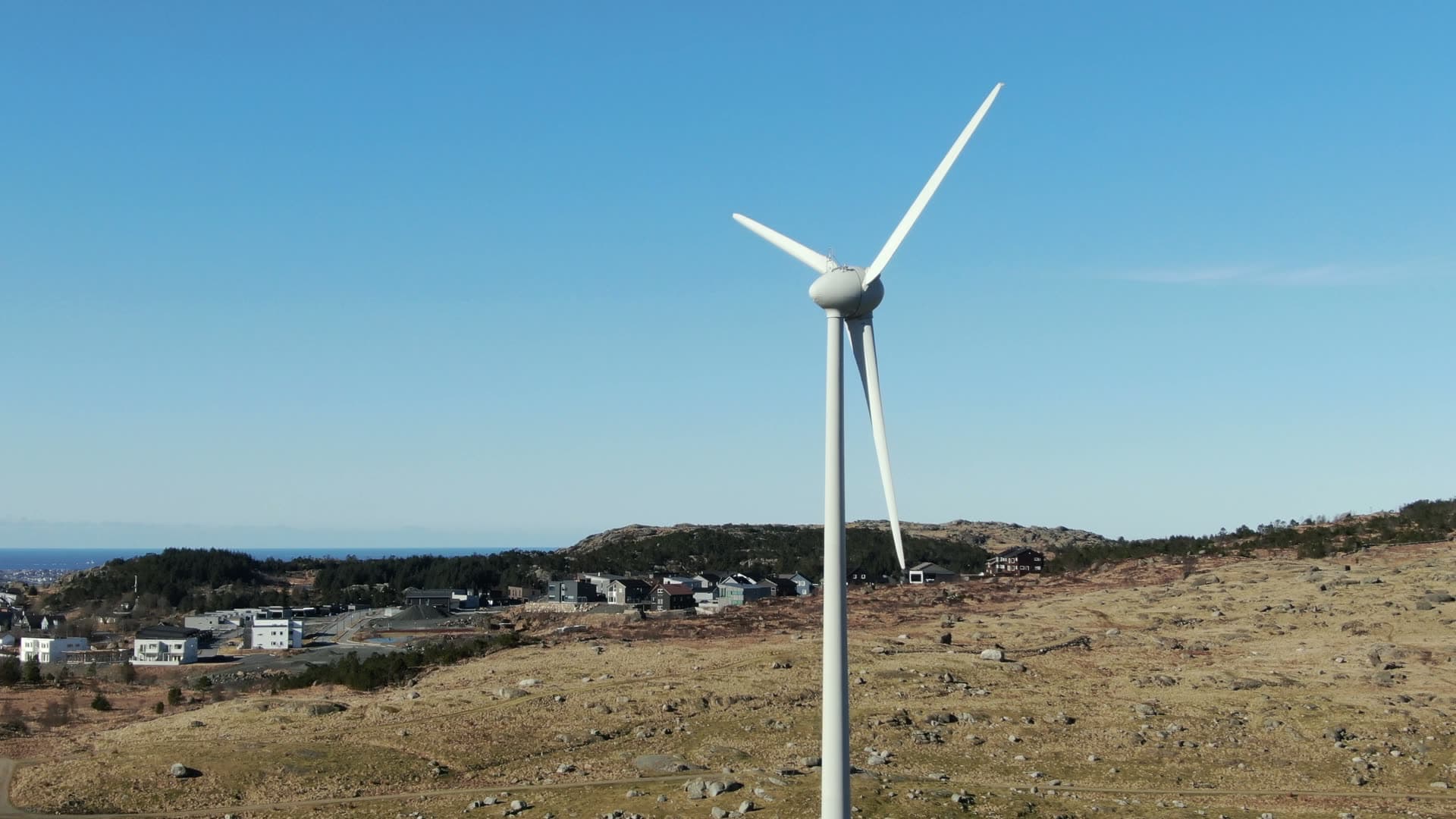 Small wind turbine rotating on hillside, Rogaland