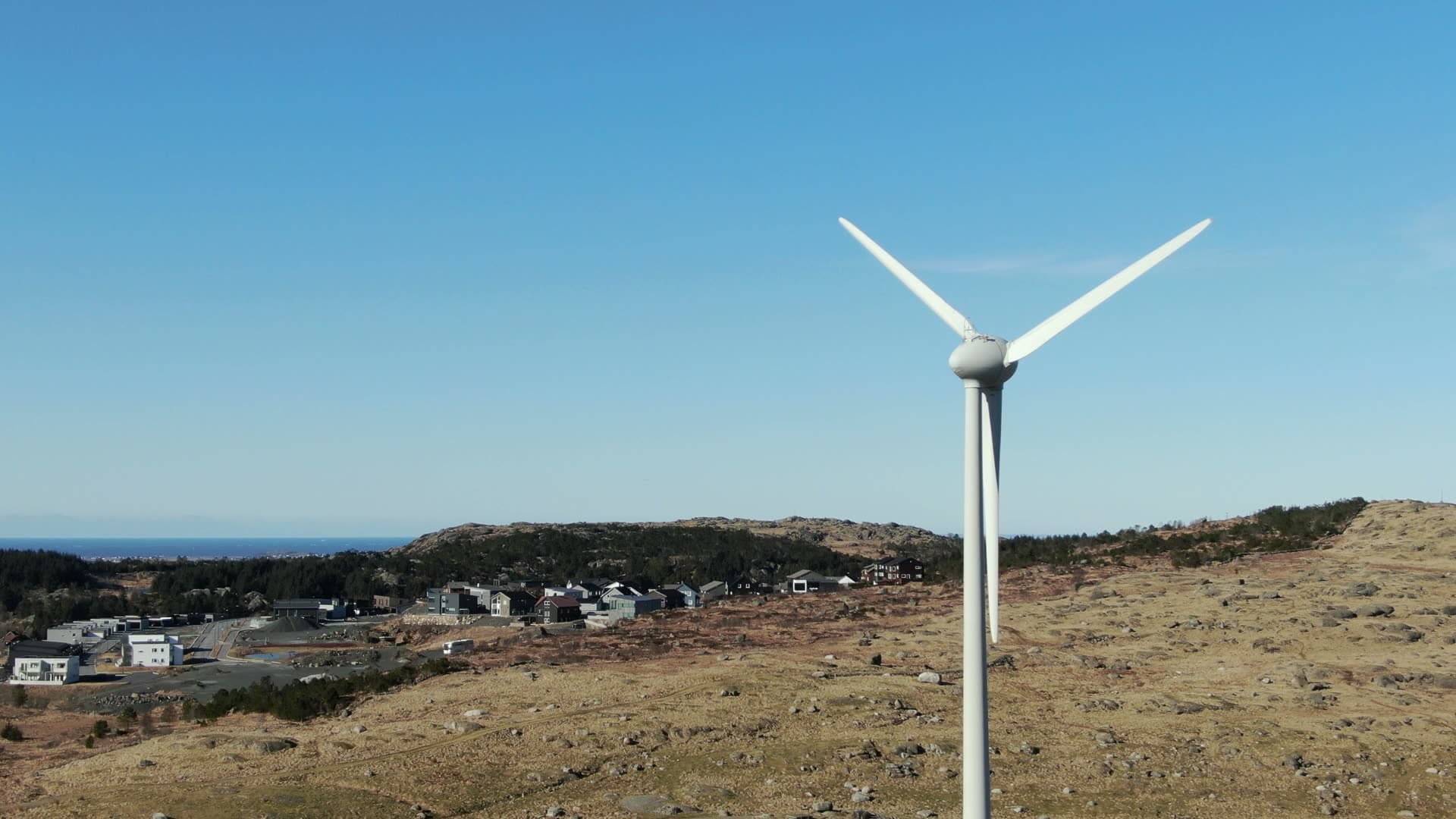 Rotating wind turbine overlooking hillside town, Rogaland
