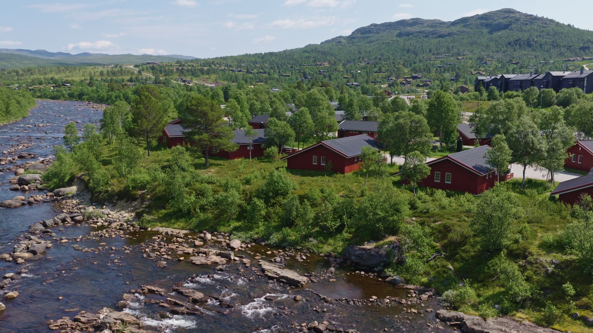 Red cabins riverside valley settlement, Hovden
