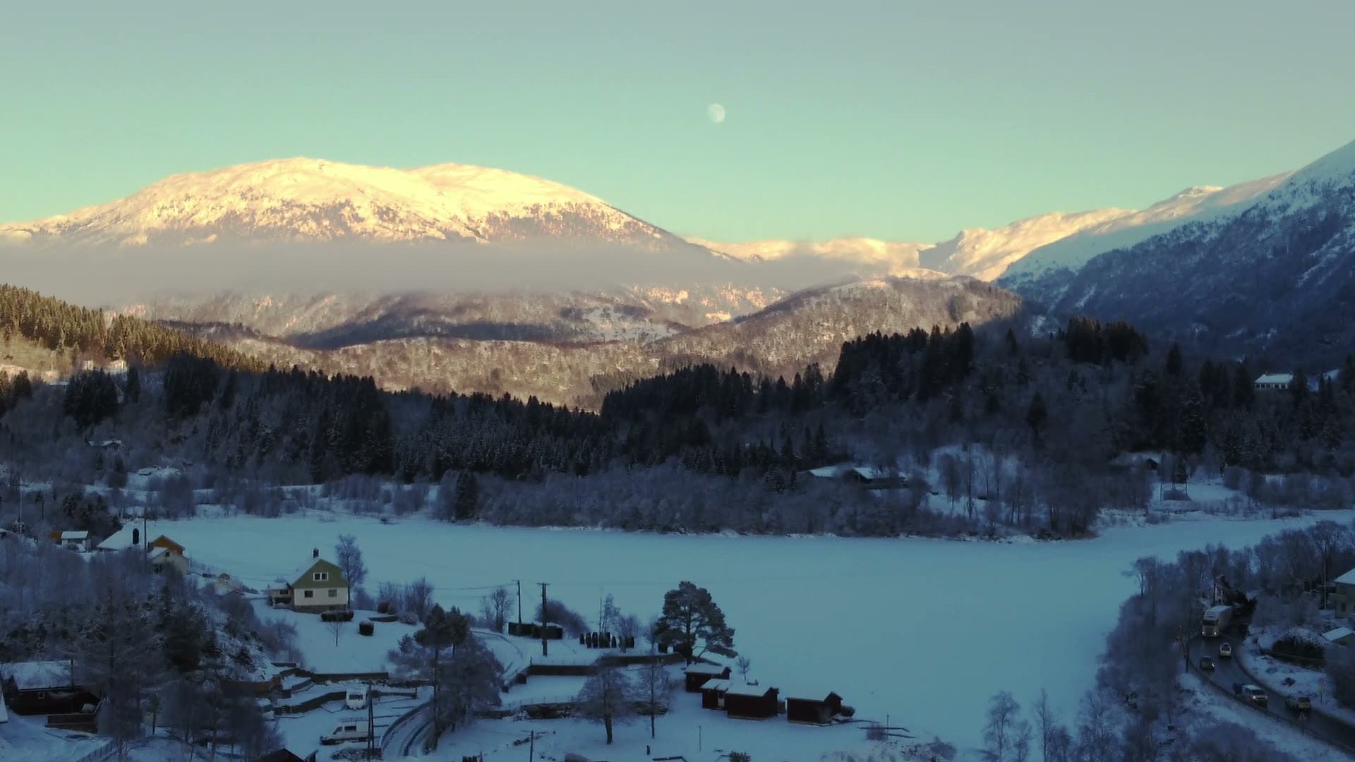 Frozen alpine lake with ski lift and valley settlement, Nesttun