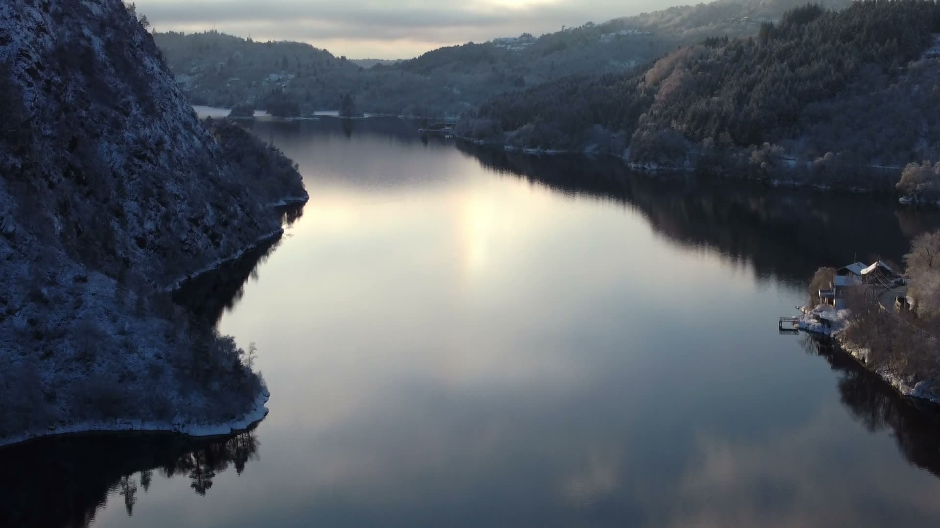 Snow-covered cliffs above frozen lake, Nesttun