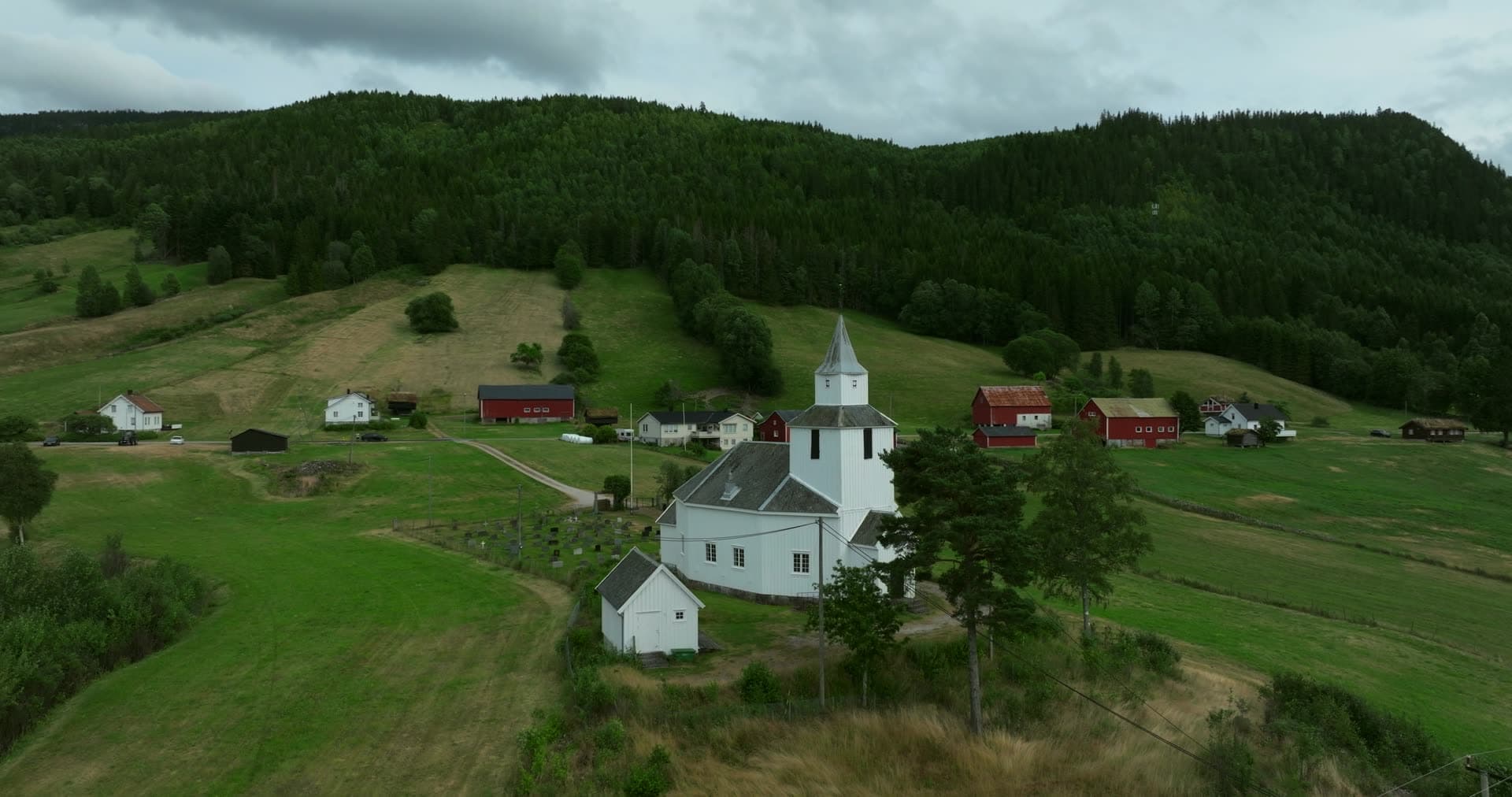 White church and graveyard among red farms, Åraksbø, Norway