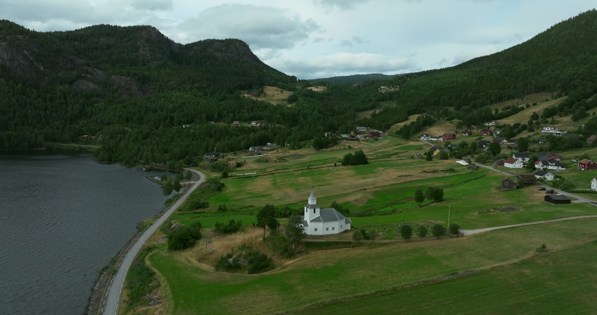 White church on a hill above the lakeside road, Åraksbø, Norway