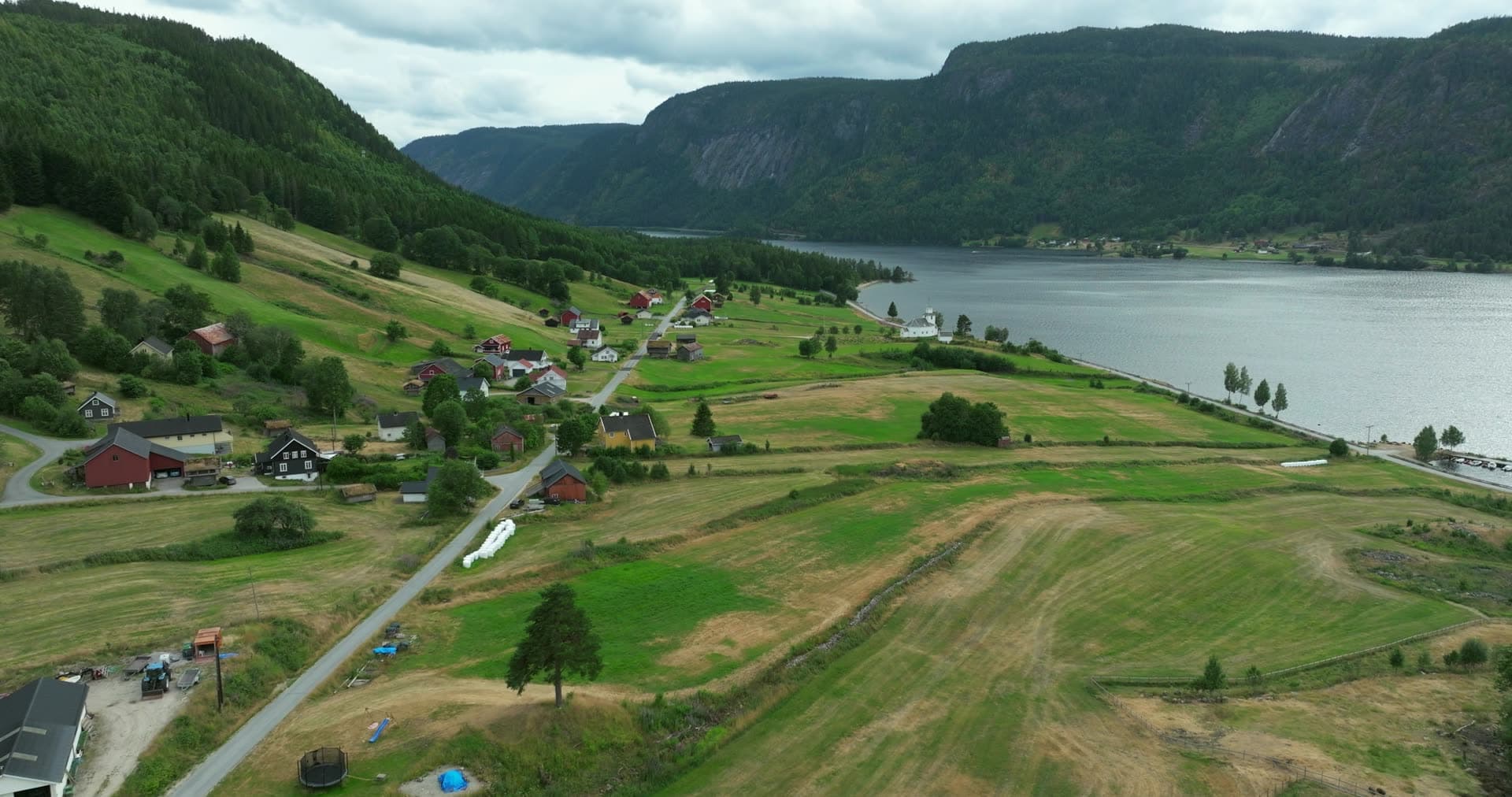 White church and mown hay fields by the lake, Åraksbø, Norway
