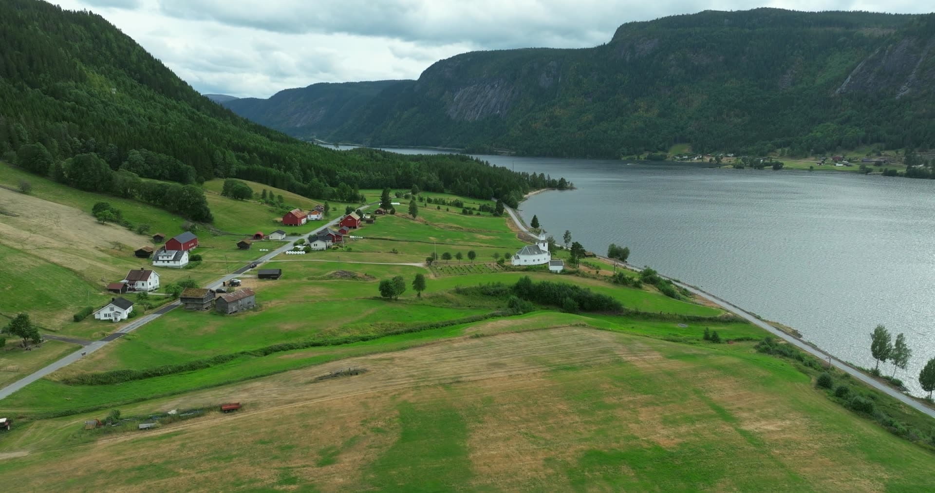 White church and red farms on lakeside fields, Åraksbø, Norway