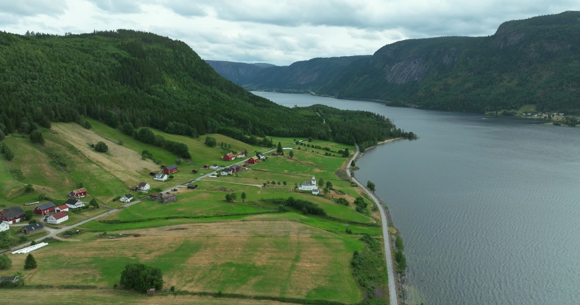 White church and farms on lakeside road, Åraksbø, Norway