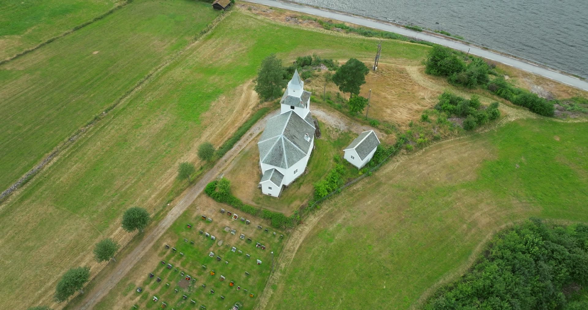 White octagonal church and graveyard by the lake, Åraksbø, Norway