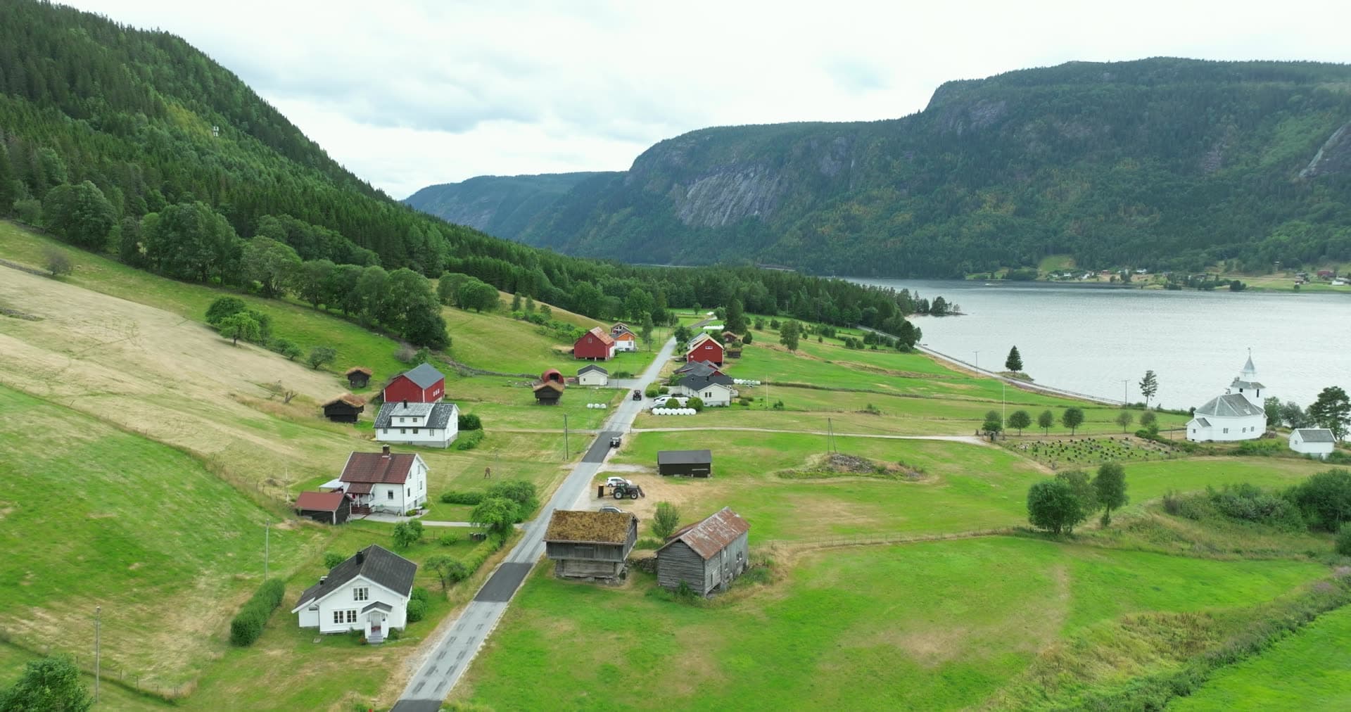 White church and turf-roofed barns by the lake, Åraksbø, Norway