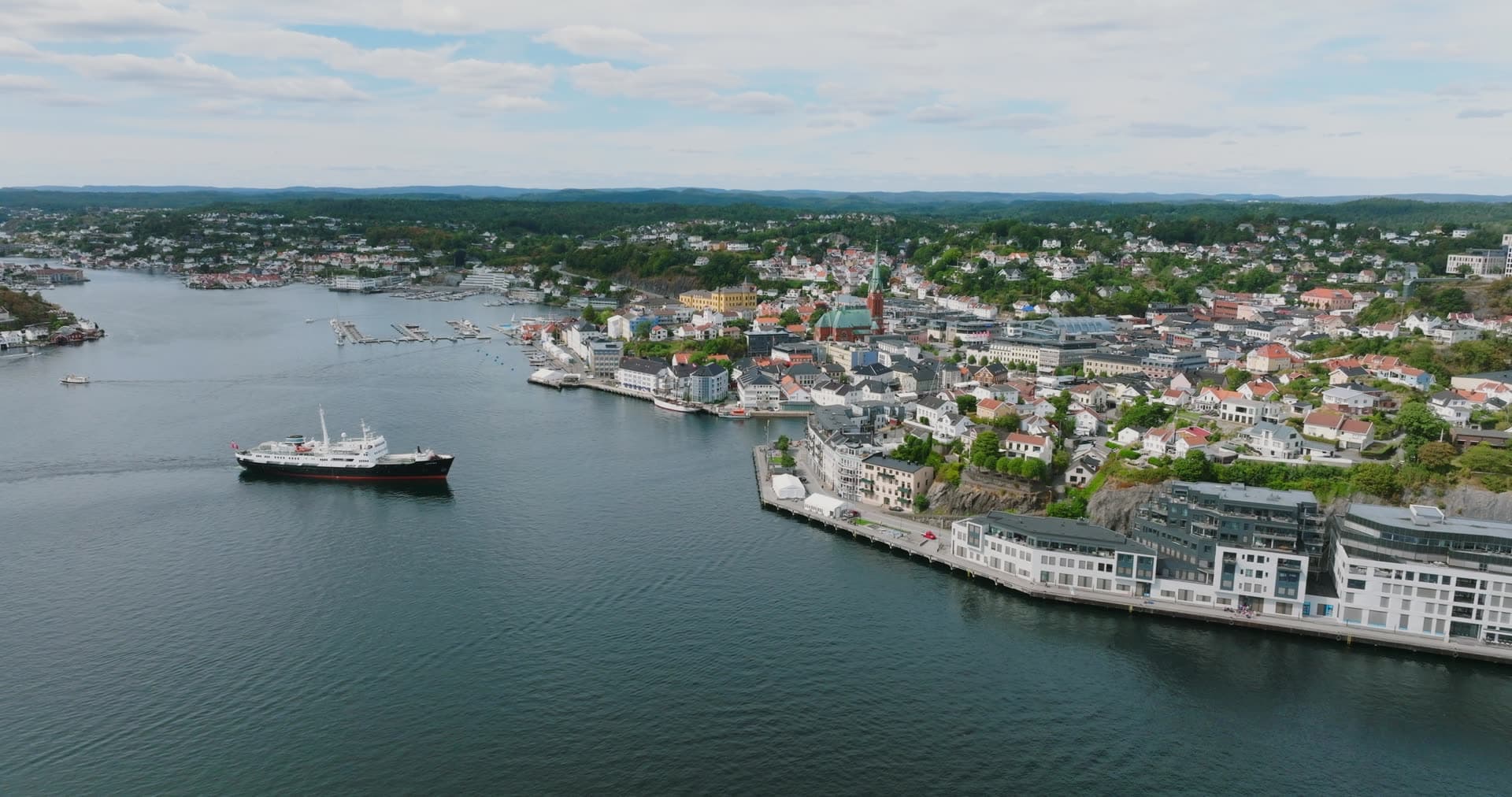 Ship passing waterfront apartments and church tower, Arendal, Norway