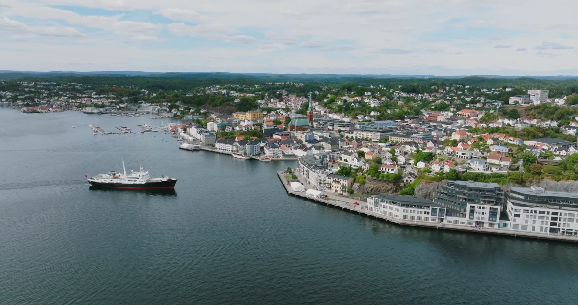 Ship passing white waterfront apartments, Arendal, Norway