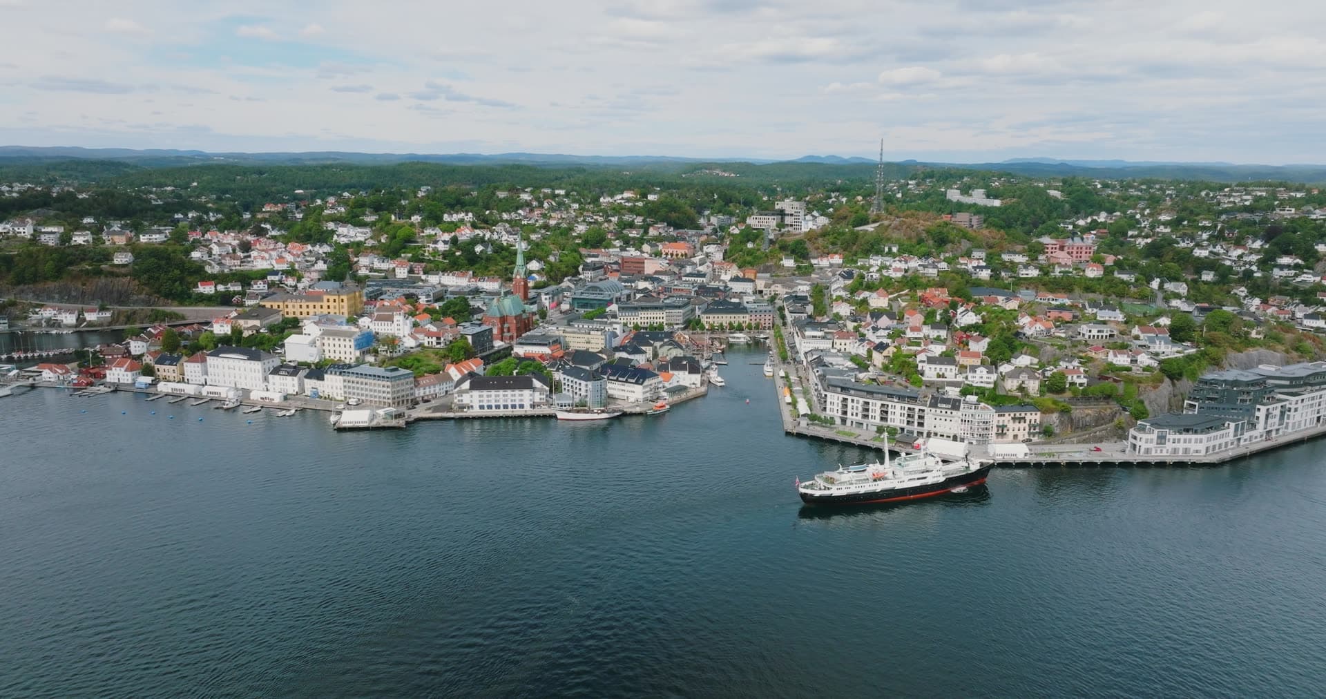 Black-hulled ship moored at quay by town centre, Arendal, Norway