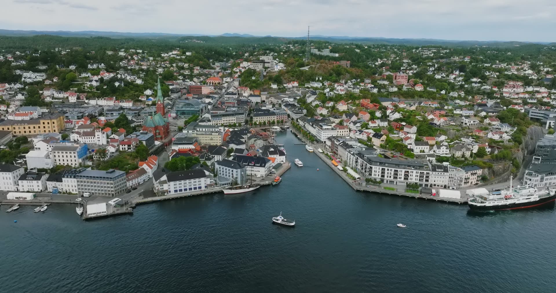Boat entering harbour channel by church spire, Arendal, Norway