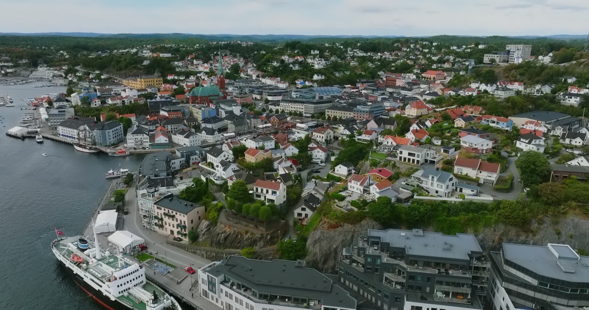 Cruise ship at quay below cliffside houses, Arendal, Norway