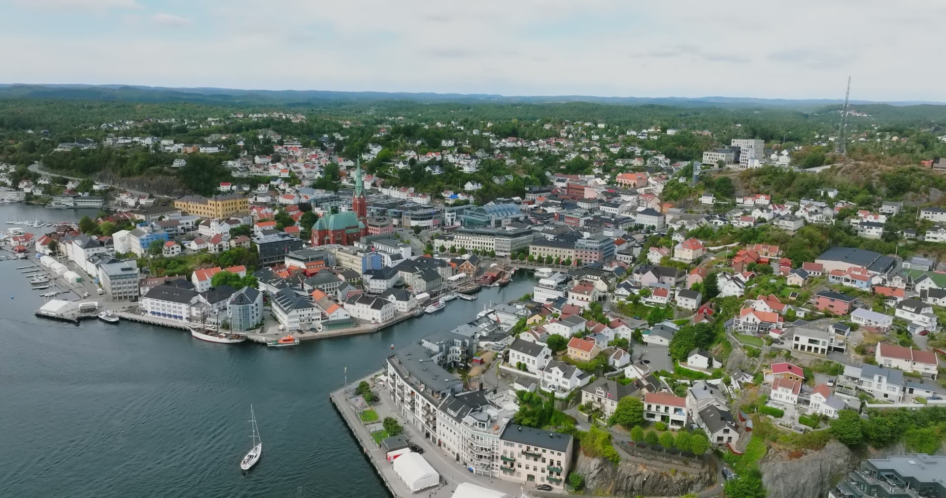 Sailboat passing town centre and church spire, Arendal, Norway