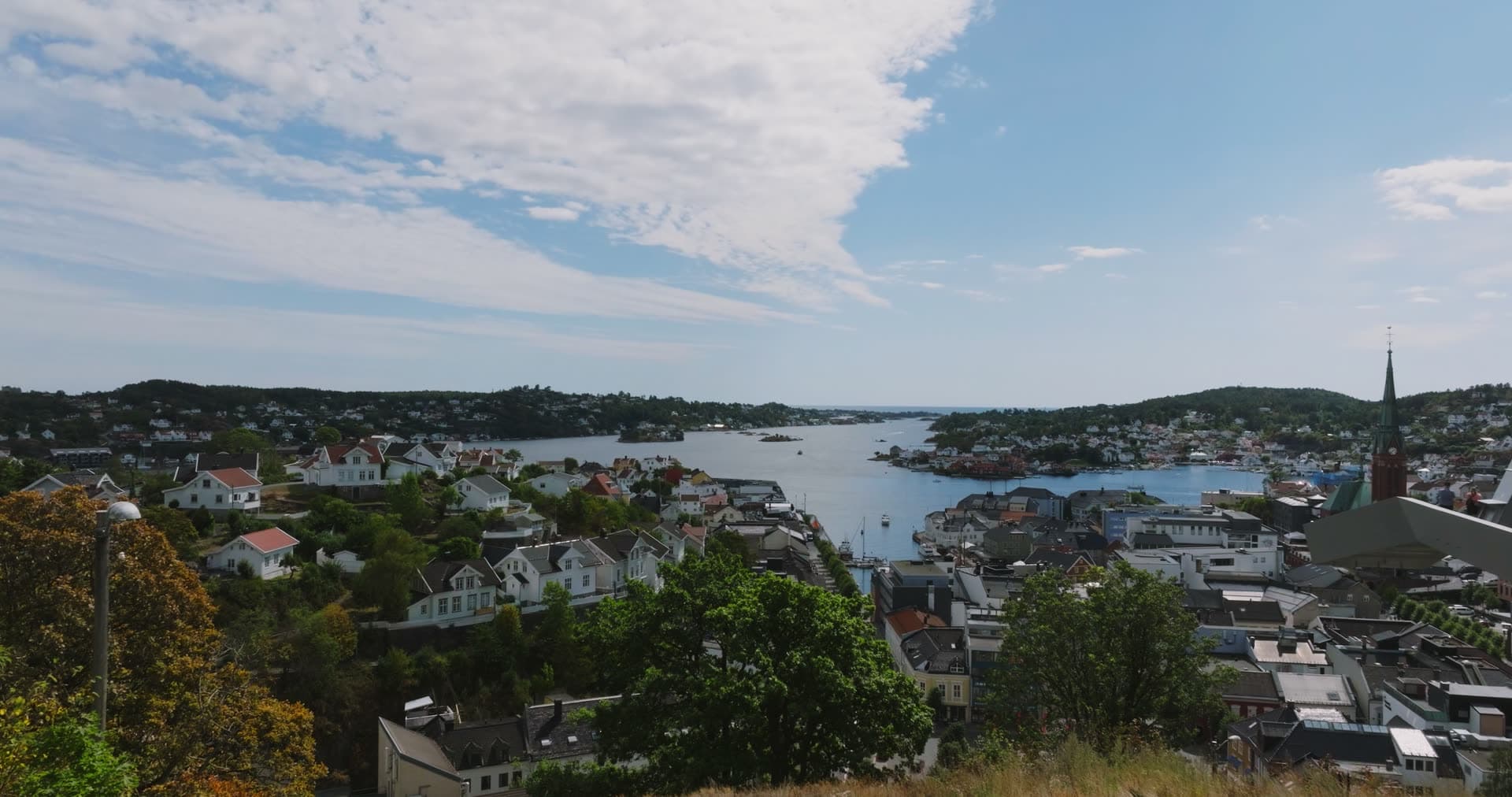Hillside white houses and church spire over the sound, Arendal, Norway