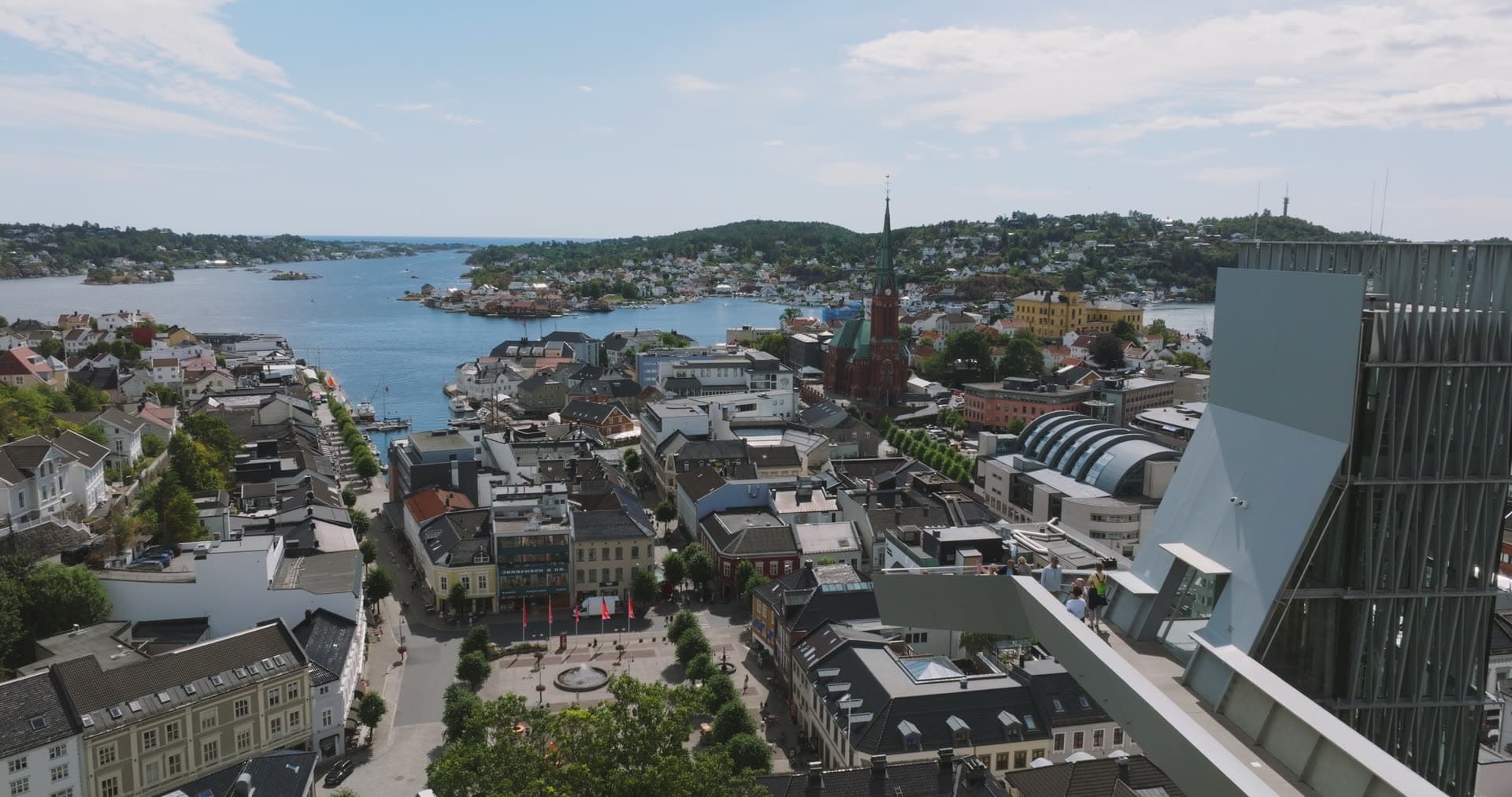 Glass high-rise above town square and church spire, Arendal, Norway
