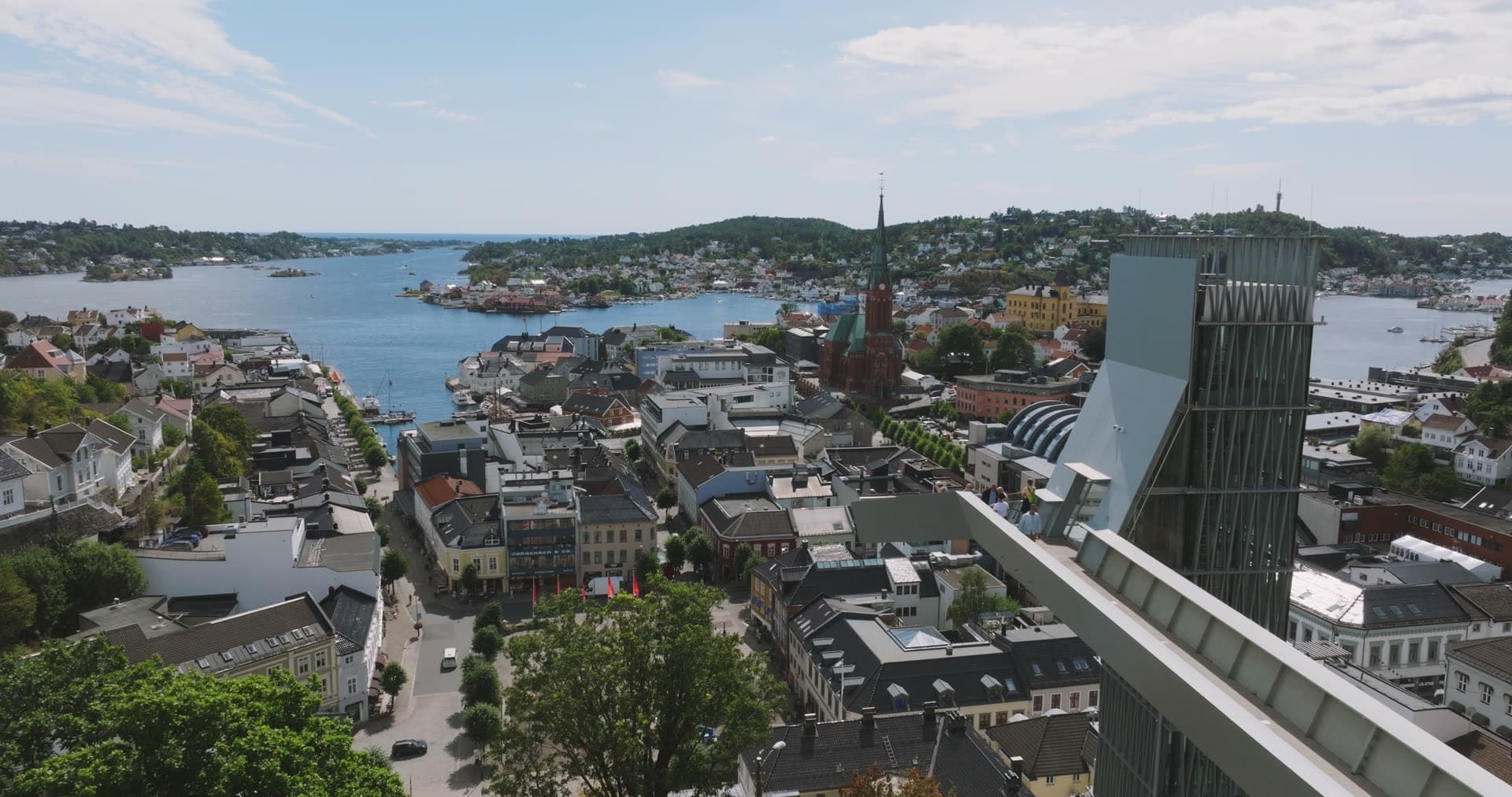 Glass tower lift and church spire over town, Arendal, Norway