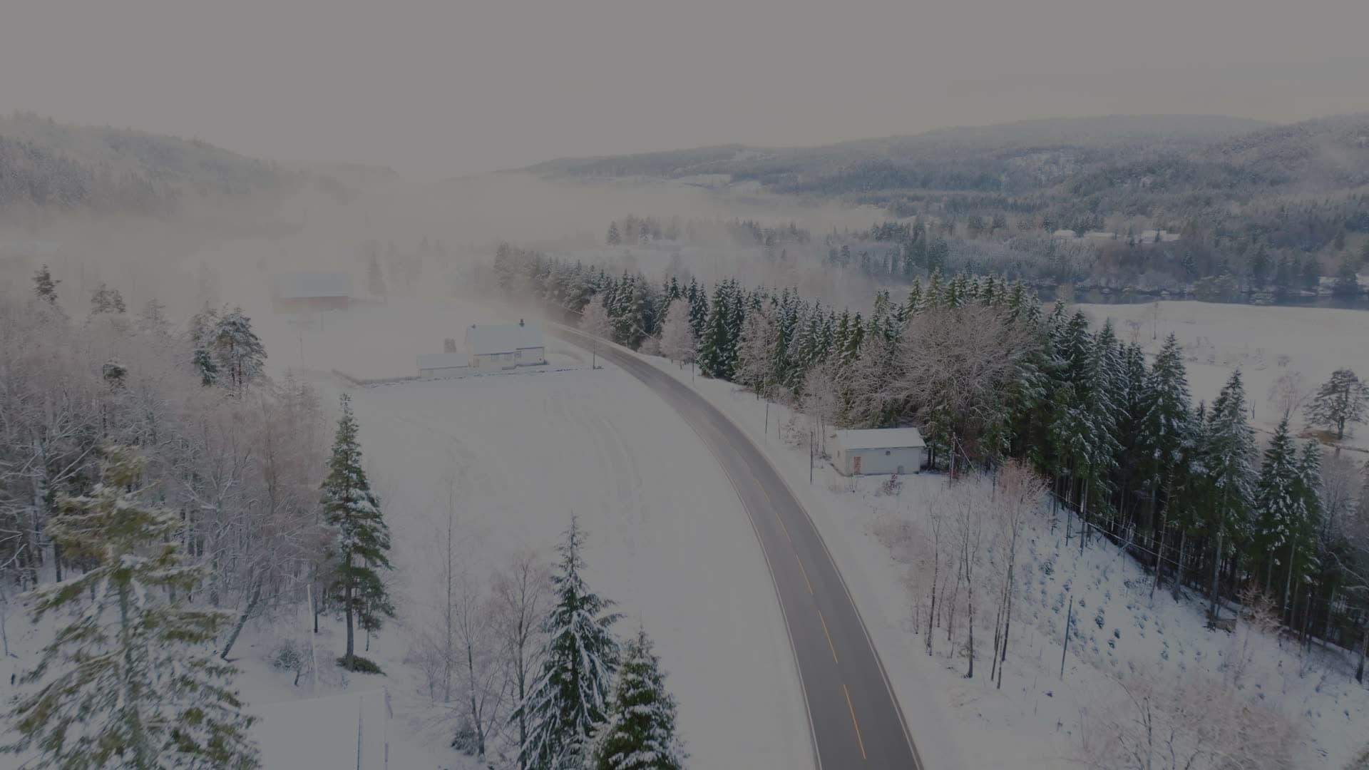 Empty road past snowed-in farm in mist, Birkeland, Norway