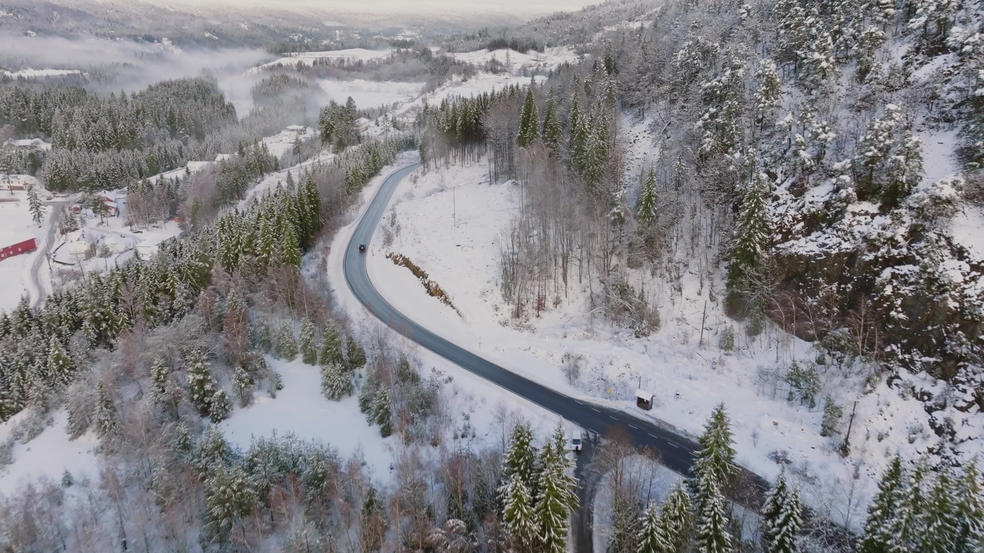 Car on winding road through snowy spruce valley, Birkeland, Norway
