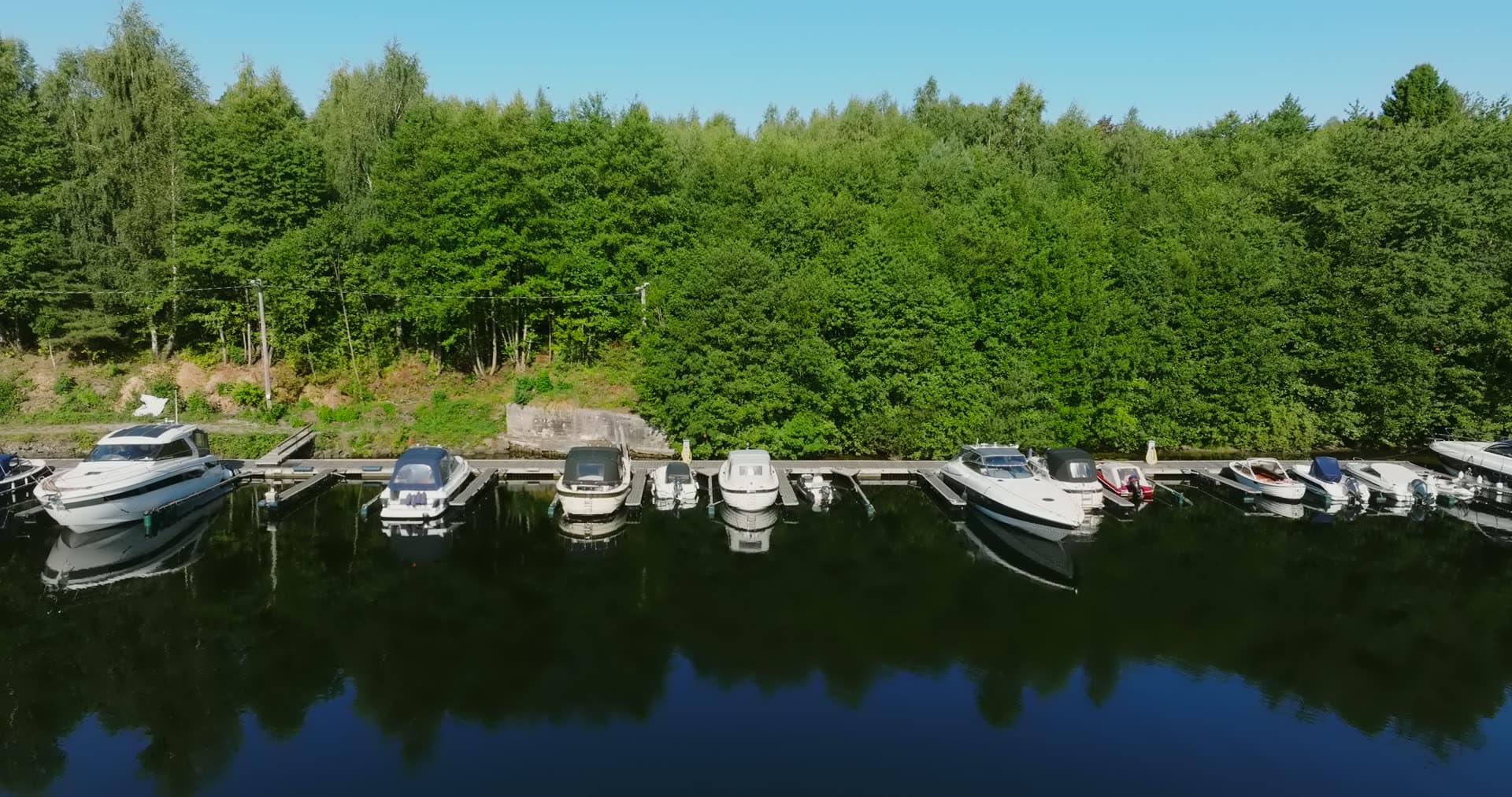 Motorboats moored along wooded shore quay, Bomsholmen, Norway