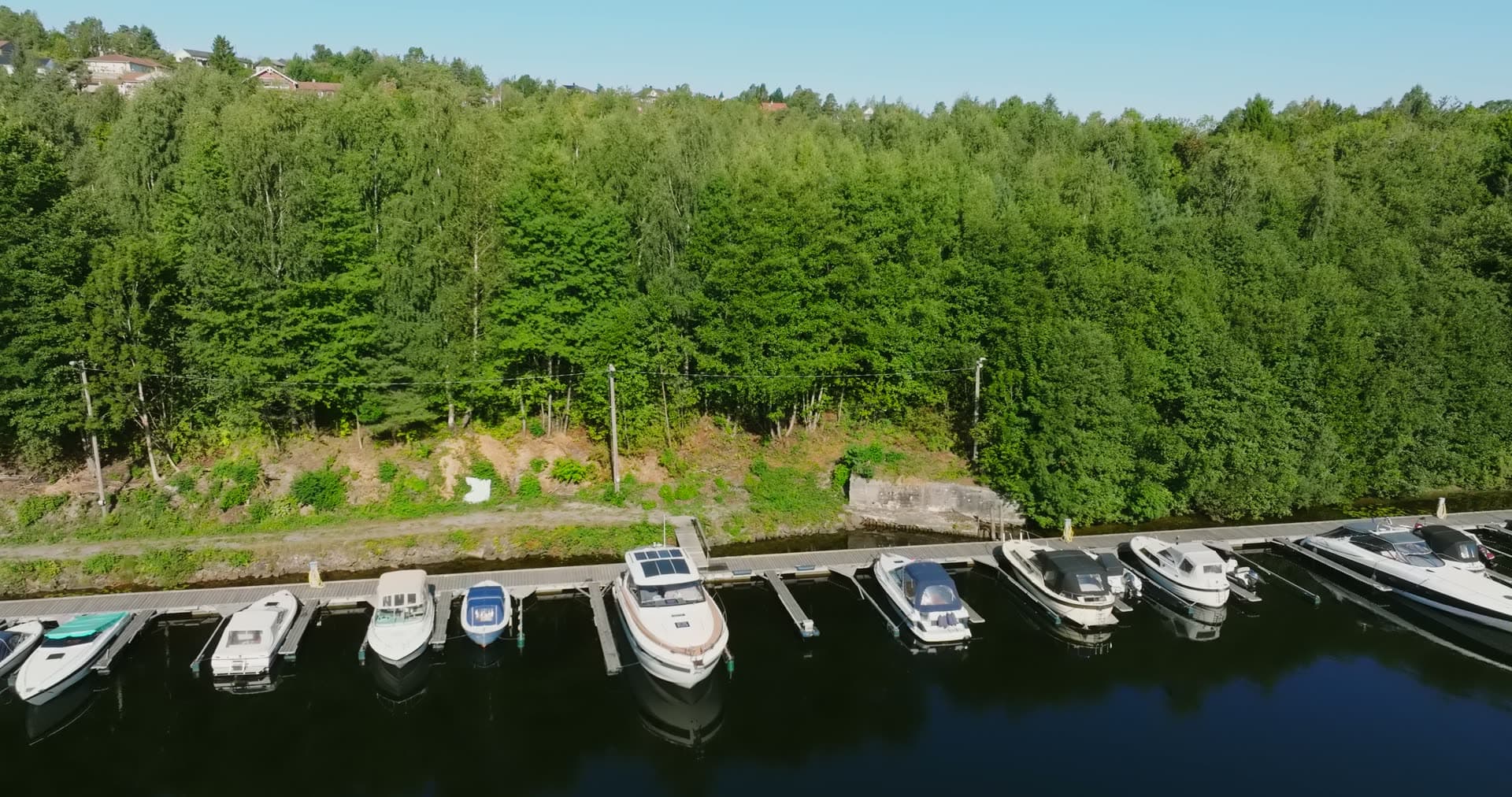 Row of boat slips below forest road, Bomsholmen, Norway
