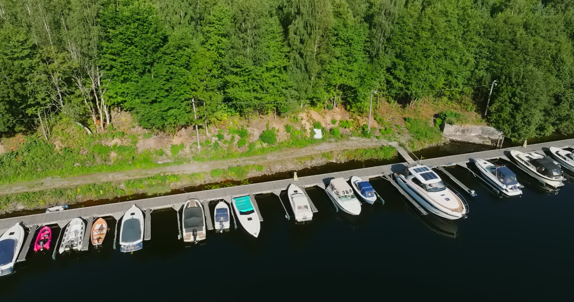 Row of motorboats at forest-edge dock, Bomsholmen, Norway