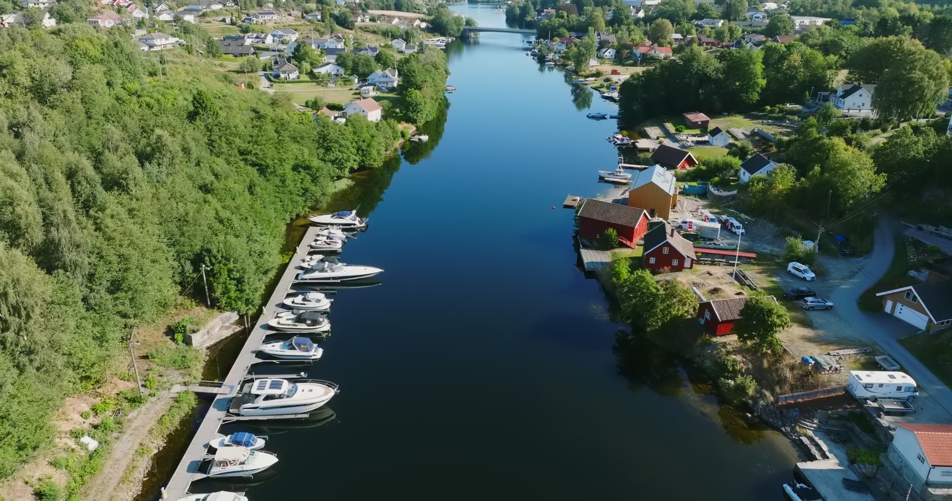 Boats along canal quay by red boathouses, Bomsholmen, Norway