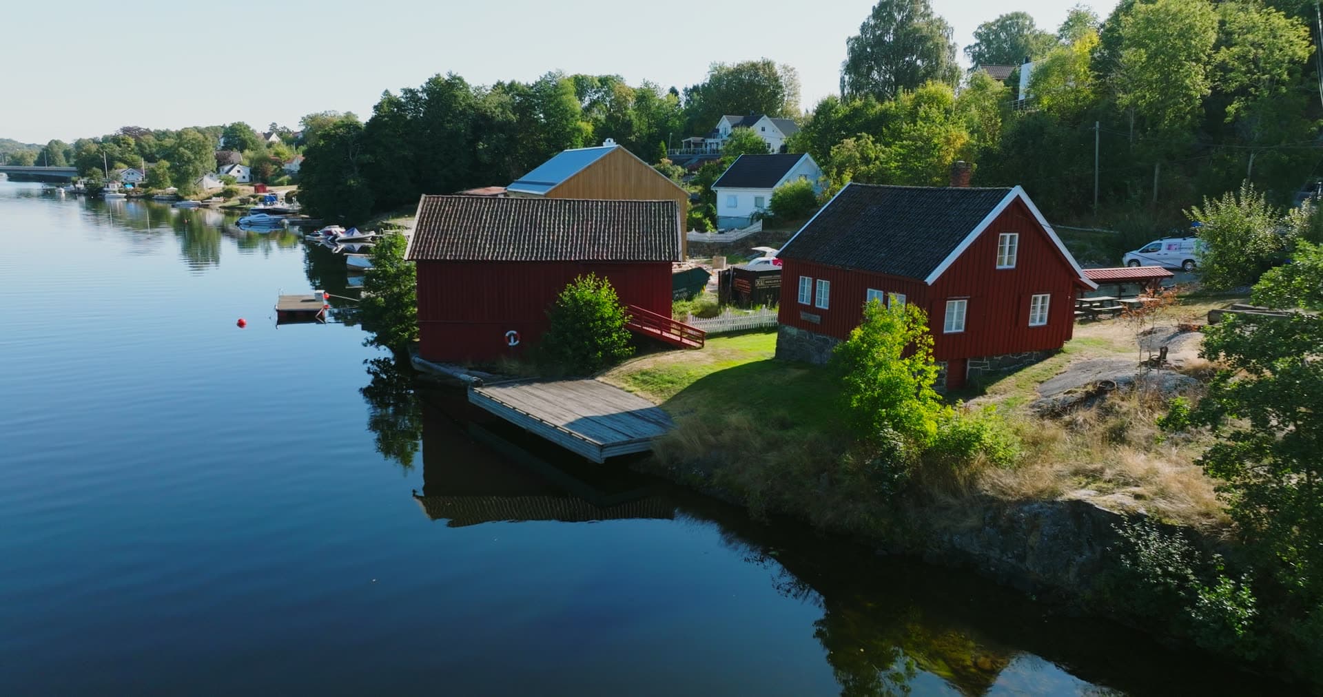 Red boathouse and cabin on calm inlet, Bomsholmen, Norway