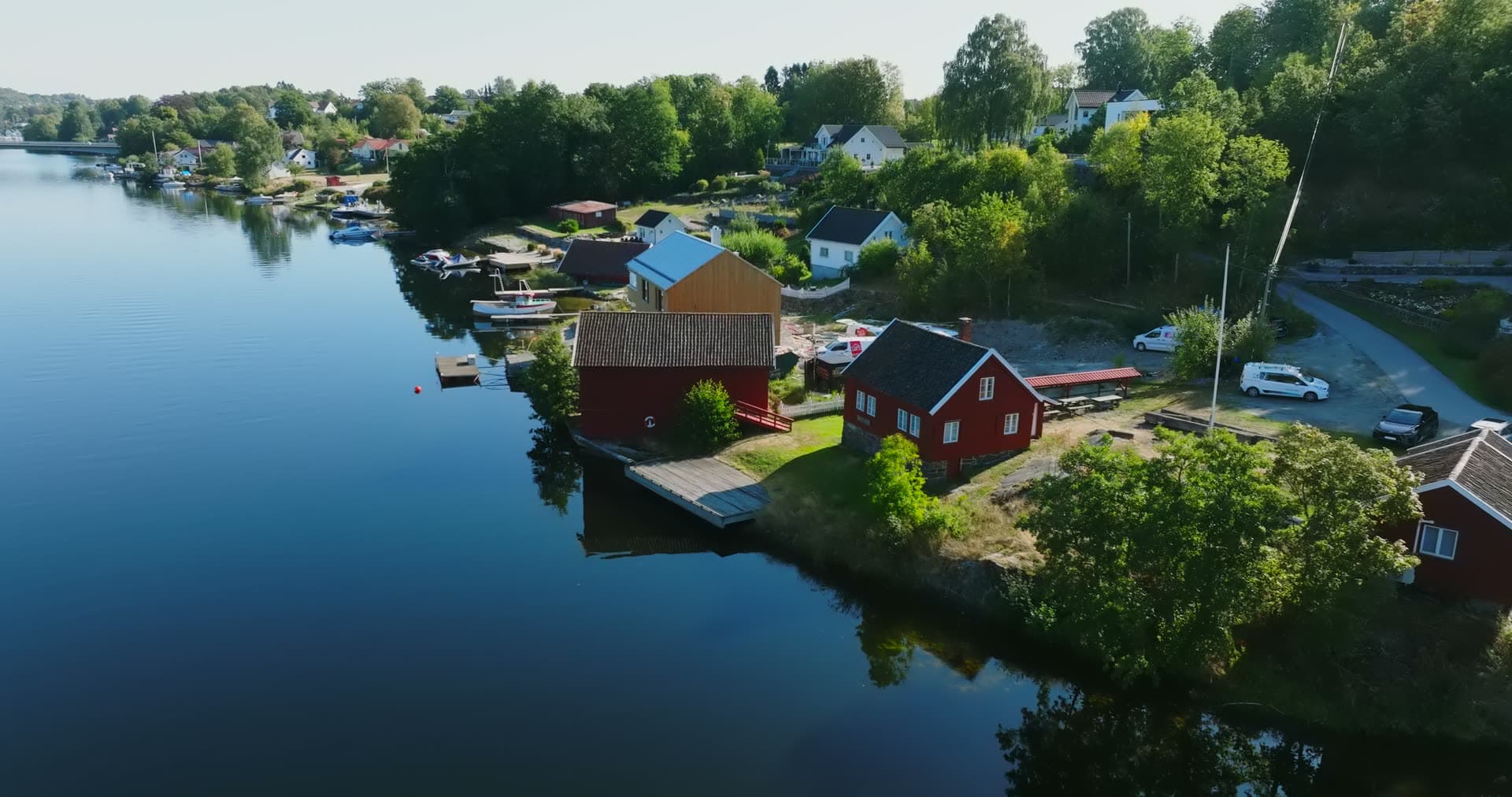 Red boathouses and dock on calm inlet, Bomsholmen, Norway