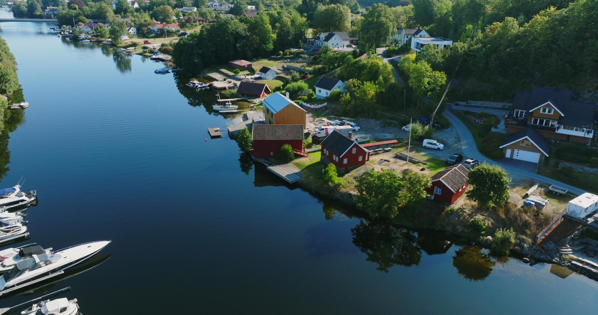 Red boathouses and motorboat docks on inlet, Bomsholmen, Norway