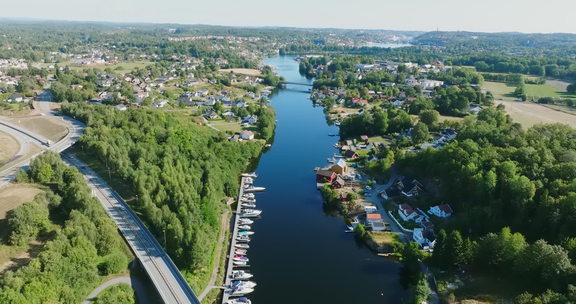 Boat docks along river beside highway, Bomsholmen, Norway