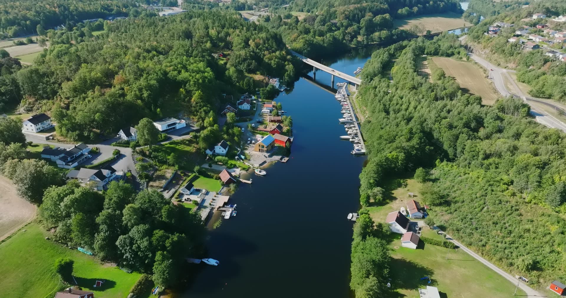 River marina and boathouses below bridge, Bomsholmen, Norway