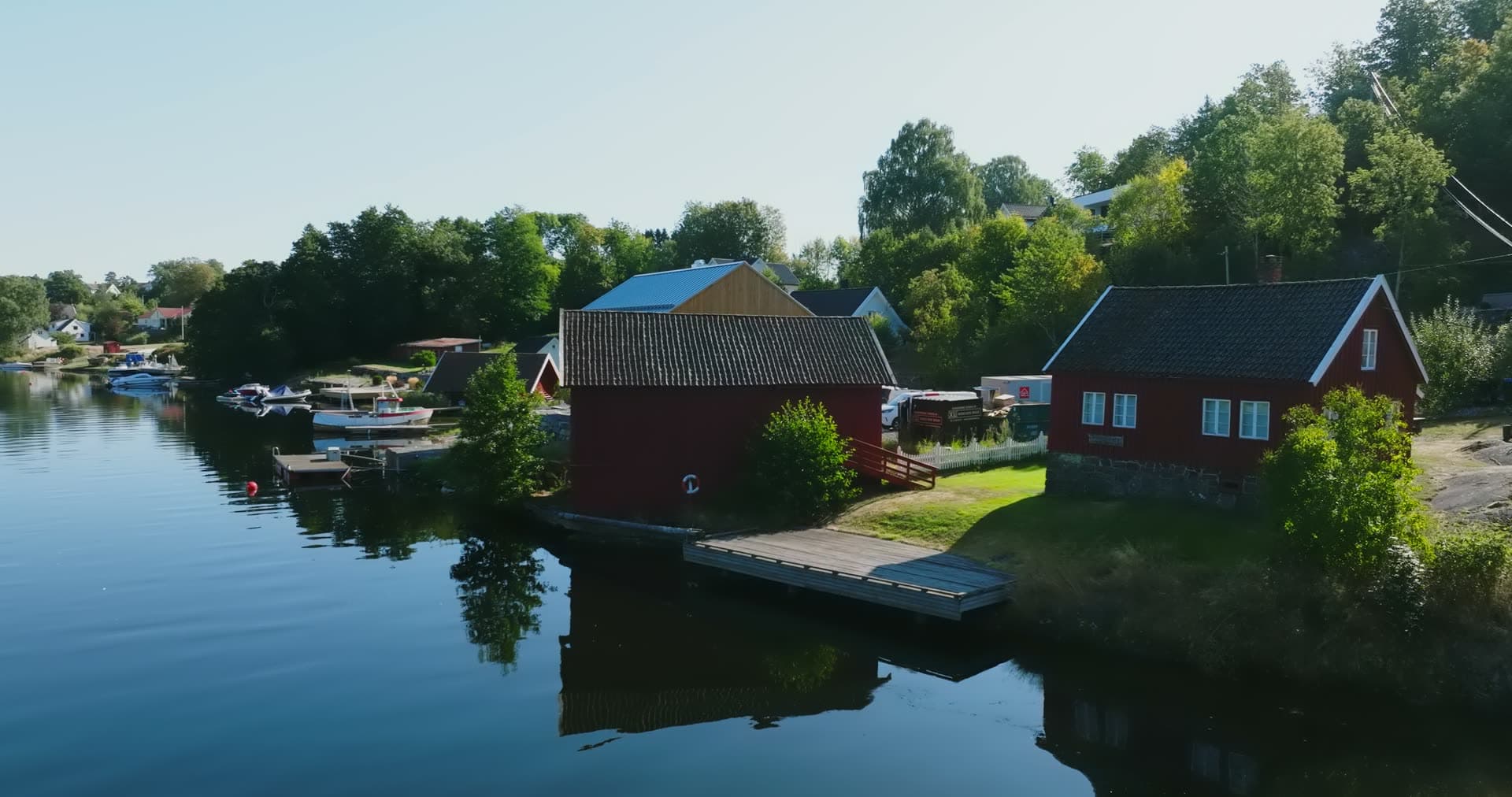 Red boathouse and floating dock on inlet, Bomsholmen, Norway