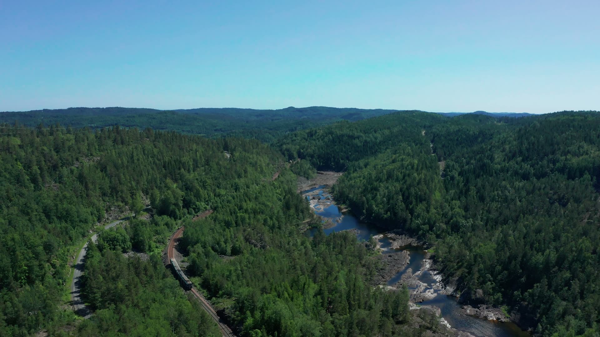 Train on forest railway above rocky river, Bøylefoss, Norway