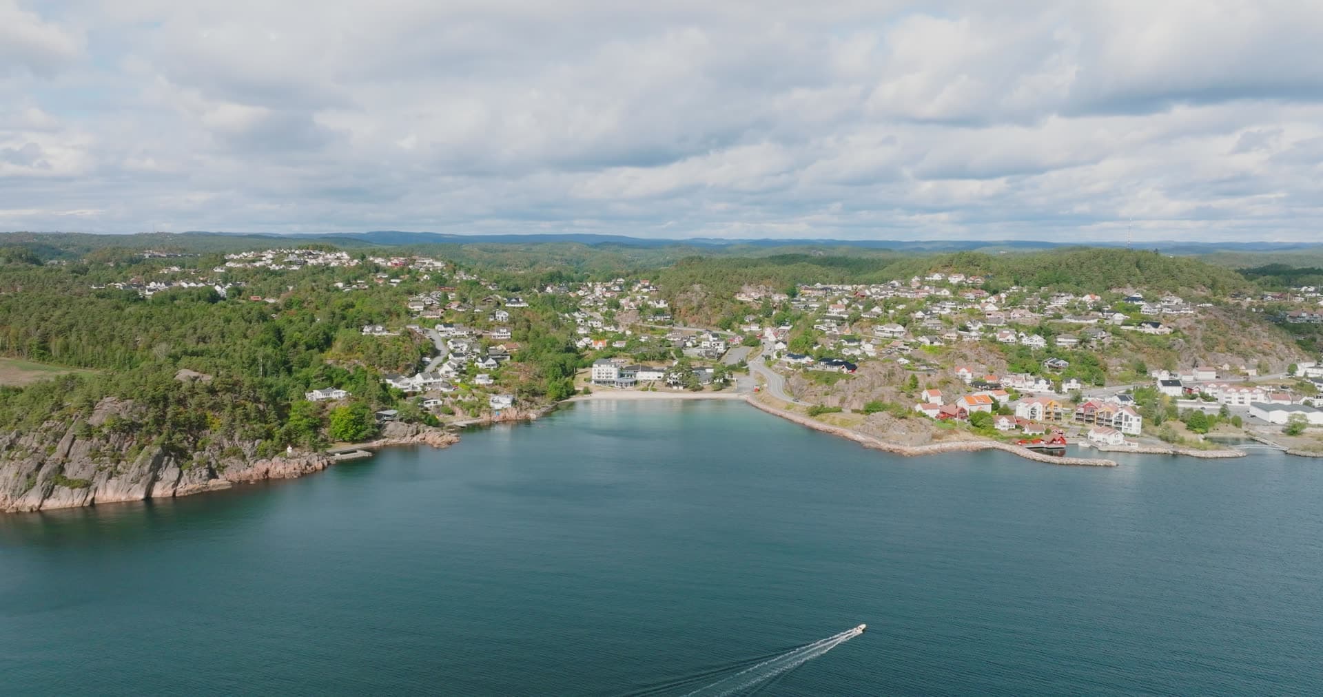 Small boat wake crossing bay by beach, Fevik, Norway