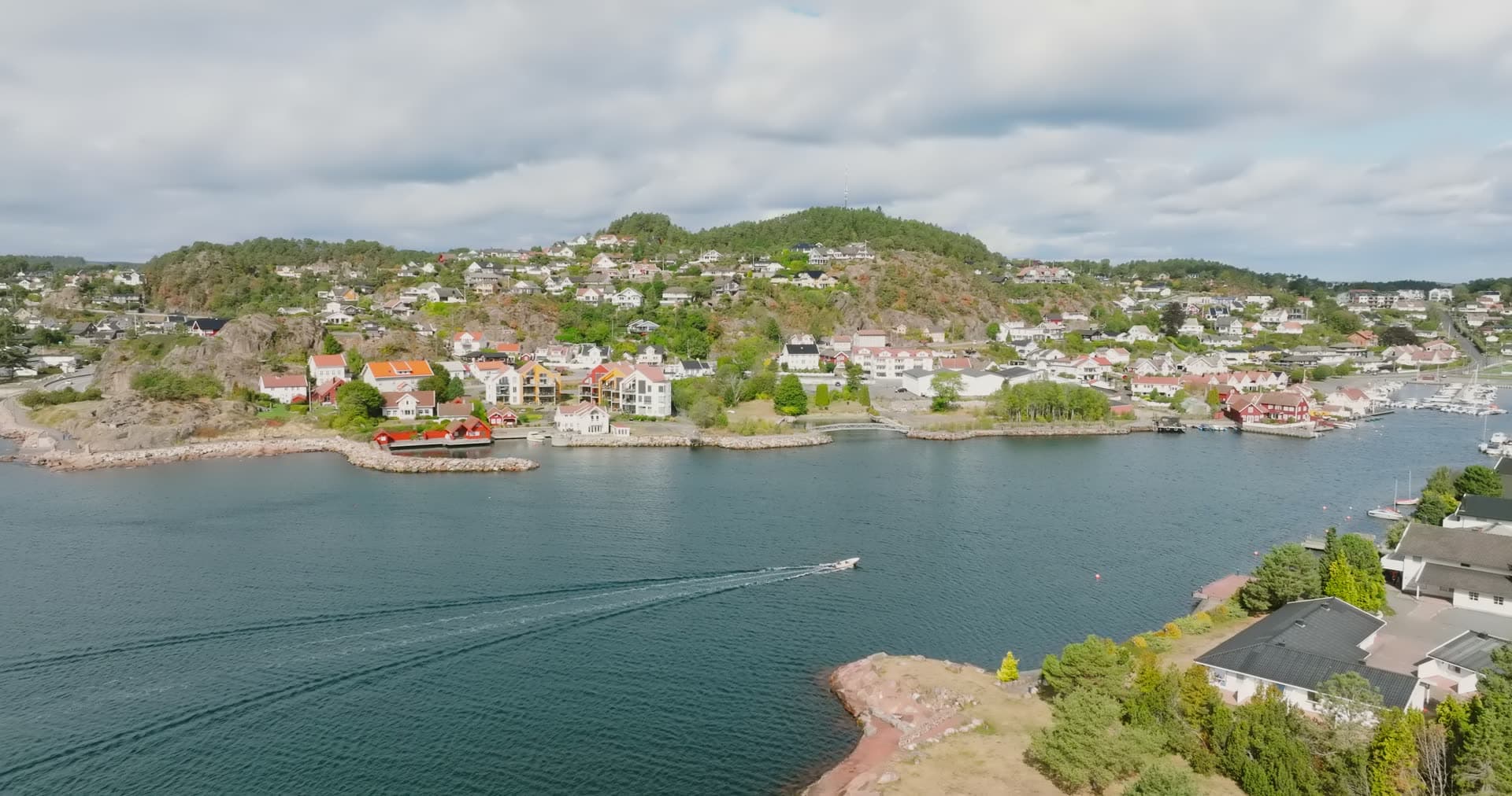 Boat wake in strait past hillside houses, Fevik, Norway
