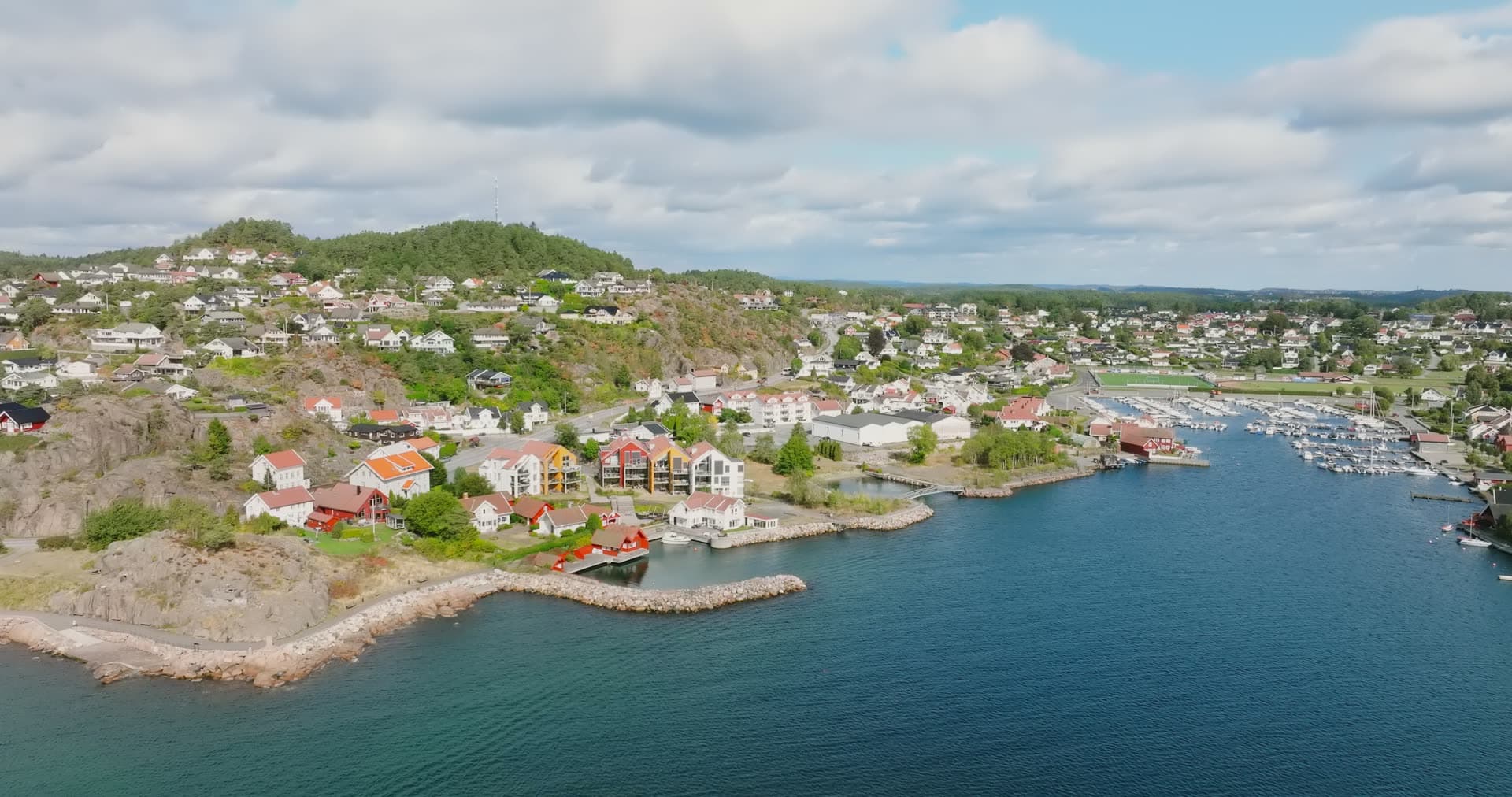 Rocky shoreline houses beside boat marina, Fevik, Norway