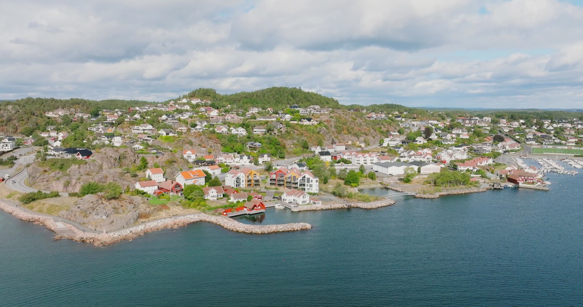 Rocky headland with houses and stone pier, Fevik, Norway